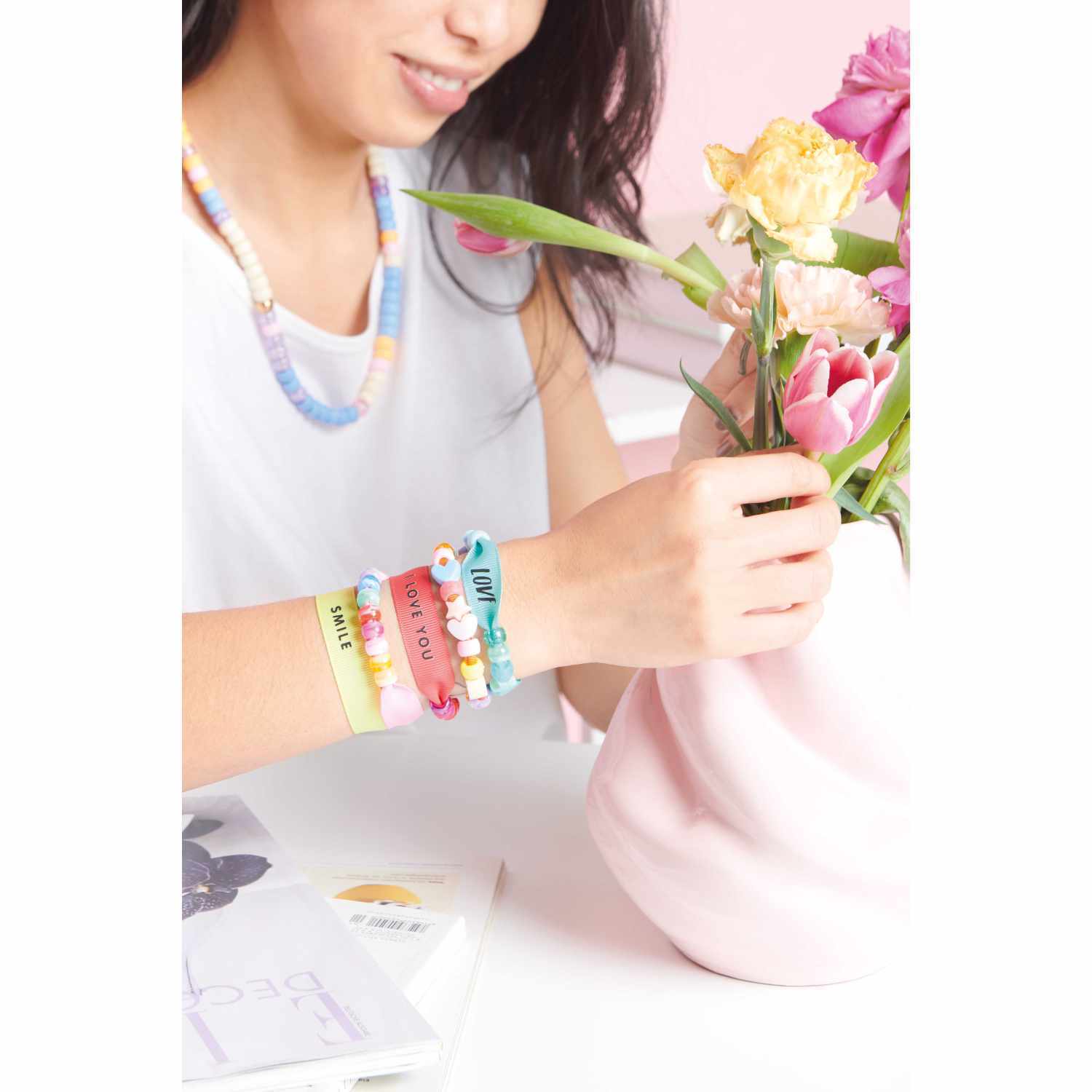 itoshii - Ponii Beads Bügelmotiv Slogans 25 Designs von Rico Design Itoshii - Ponii Beads Bügelmotiv Slogans: Frau arrangiert Blumen in Vase, trägt bunte Armbänder.