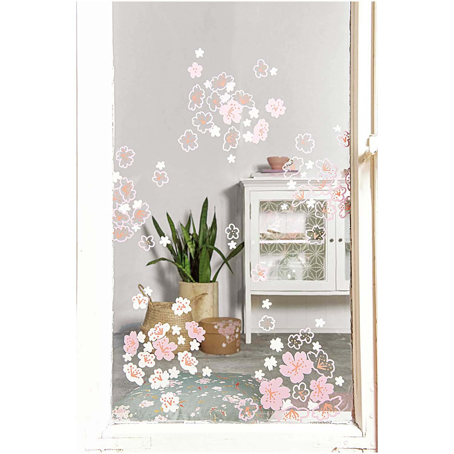 Vorlagenmappe Jardin Japonais Fenster- und Glasmalerei mit Kreidestiften von Rico Design Vorlagenmappe Jardin Japonais: Fenster mit rosa Kirschblüten, dekoriert mit Kreidestiften, im Hintergrund ein weißes Regal und grüne Pflanze.