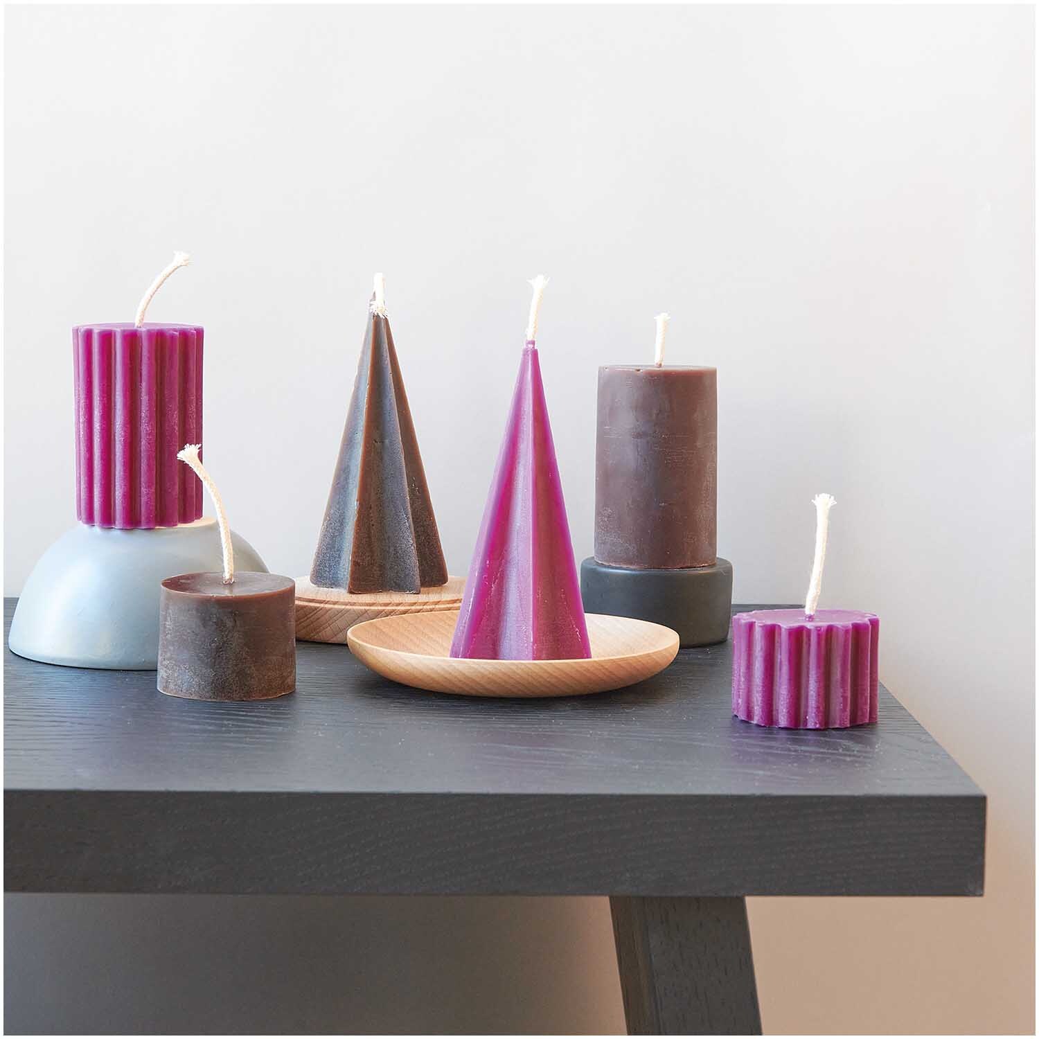 Kerzengießform Sternenkegel 70x70x135mm von Rico Design Kerzengießform Sternenkegel 70x70x135mm von Rico Design, umgeben von bunten Kerzen auf einem Tisch.