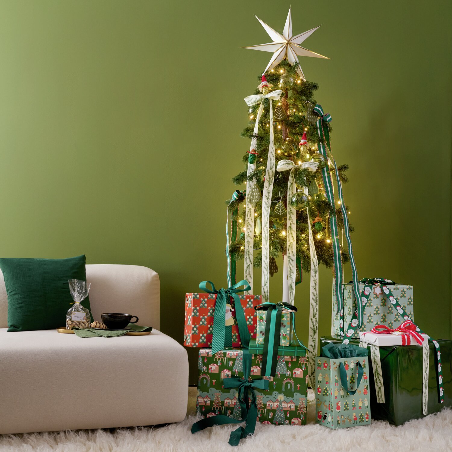 Paper Poetry bande tissée diagonale 50mm 3m Couleur Vert from Rico Design Auf dem Bild ist ein stilvoll dekorierter Weihnachtsbaum von Rico Design zu sehen, geschmückt mit handgefilzten Tannenaufhängern in Khaki. Der Baum ist umgeben von festlich verpackten Geschenken.