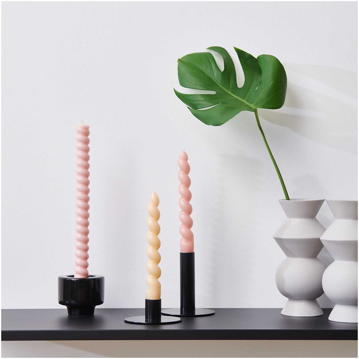 Kerzenständer schwarz von Rico Design auf einem Regal mit gedrehten Kerzen und Monstera-Blatt.
