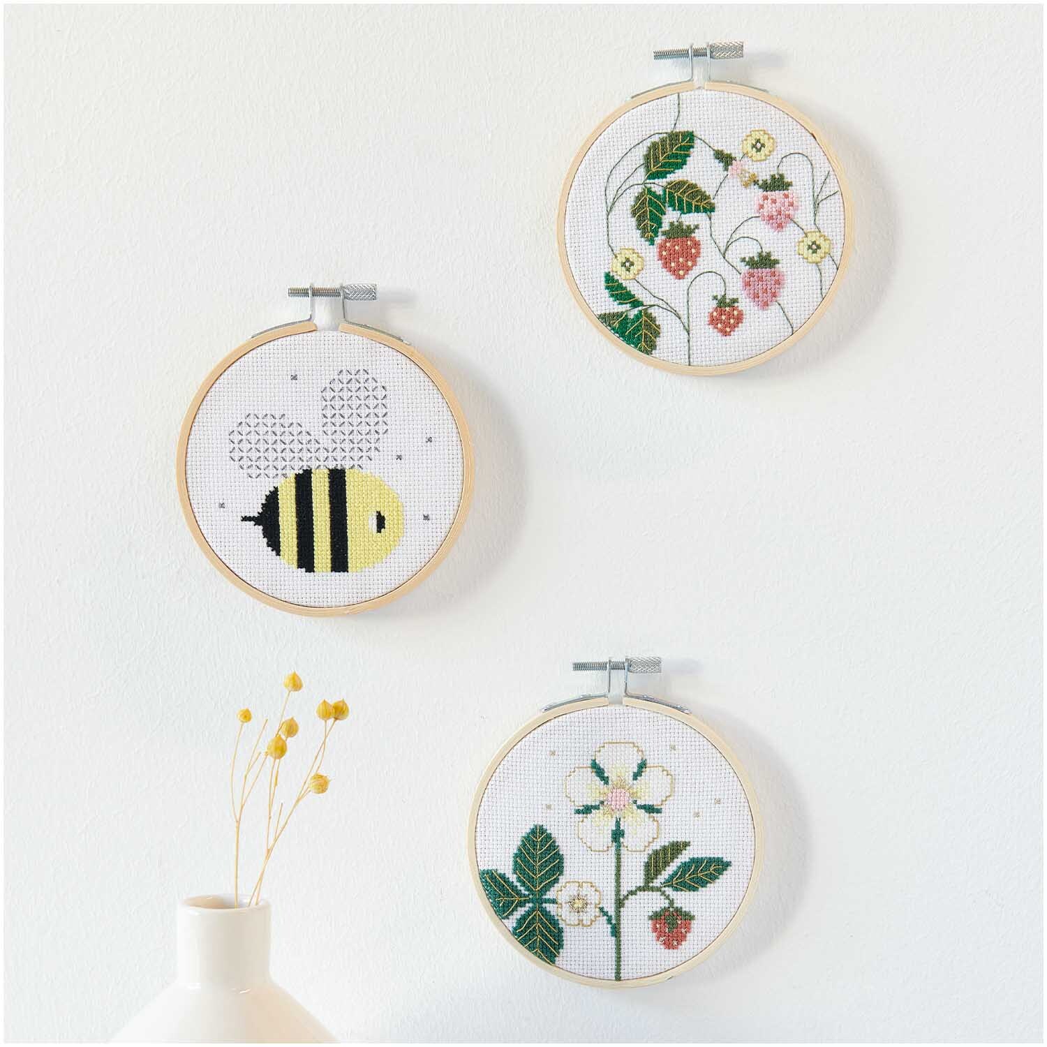 Paquet à broder image abeille Ø10cm from Rico Design Stickpackung Bild Biene Ø10cm: Drei Stickrahmen mit Bienen- und Blumenmotiven von Rico Design an einer weißen Wand.