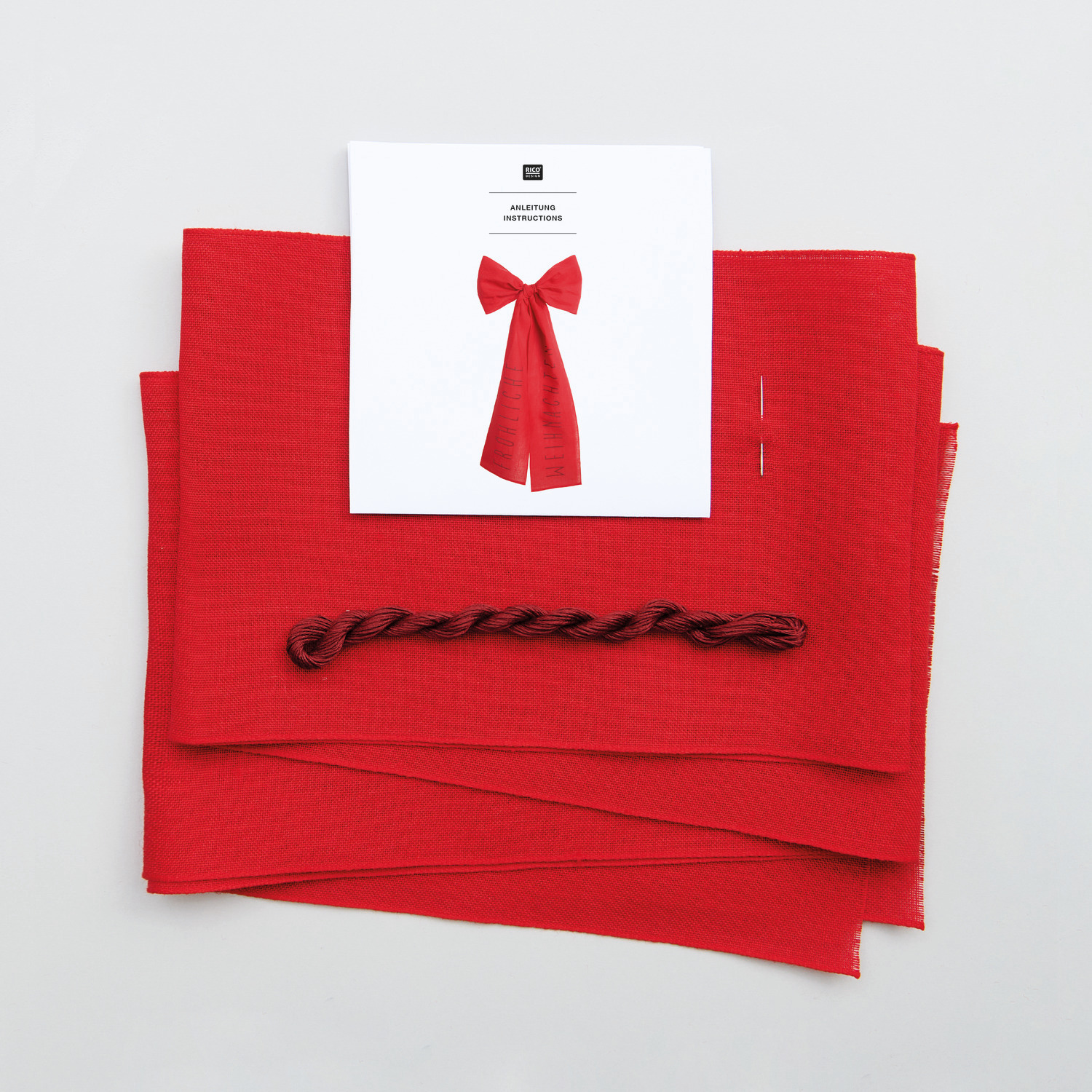 Stickpackung Schleife Fröhliche Weihnachten 38x80cm von Rico Design Stickpackung Schleife Fröhliche Weihnachten von Rico Design: Rotes Stickset mit Schleifenmotiv und Anleitung auf weißem Hintergrund.