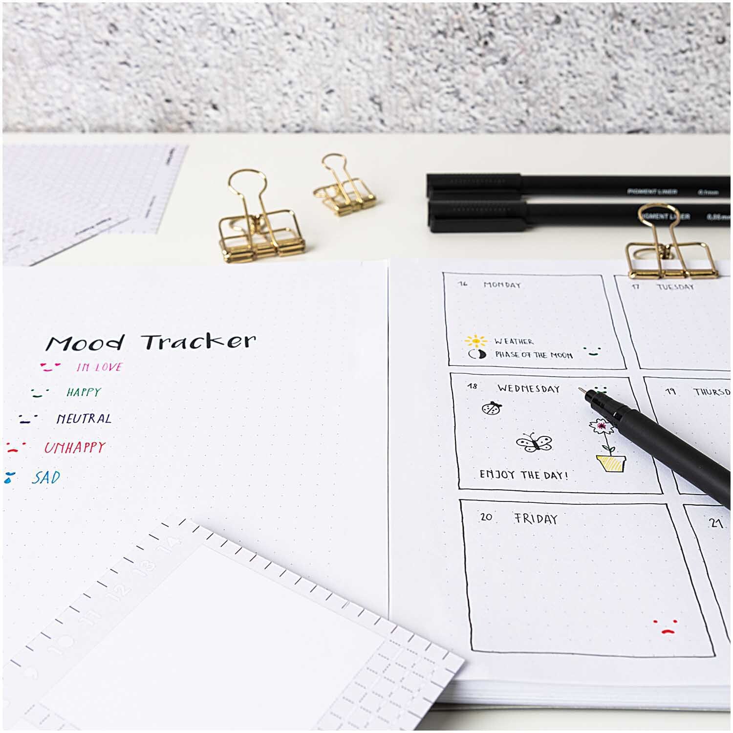 Paper Poetry Gelstifte-Set fein 0,4mm 10 Stück auf einem Schreibtisch mit Mood Tracker und Kalender. Ideal für kreative Planungen und Notizen.