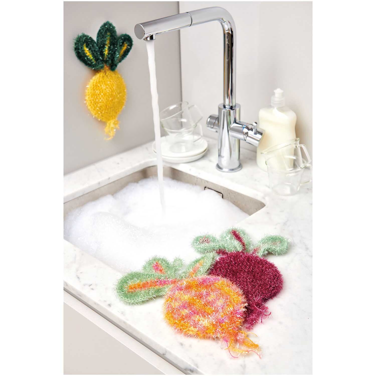 Creative Bubble Print Rübchen: Bunte Spülschwämme in Gemüseform neben einem Wasserhahn auf einer Küchenspüle.