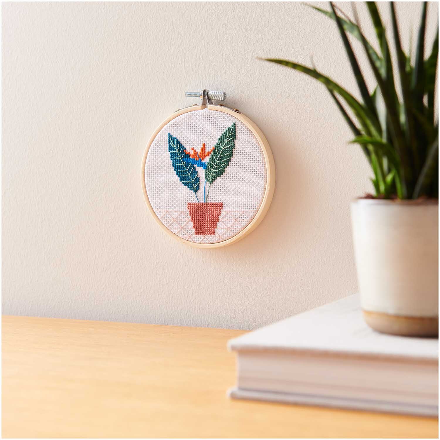 Mini Kit de broderie Image Strelitzie Ø 10cm from Rico Design Stickpackung Mini Kit Strelitzie Bild Ø 10cm zeigt eine bunte Strelitzie im Holzrahmen an der Wand.