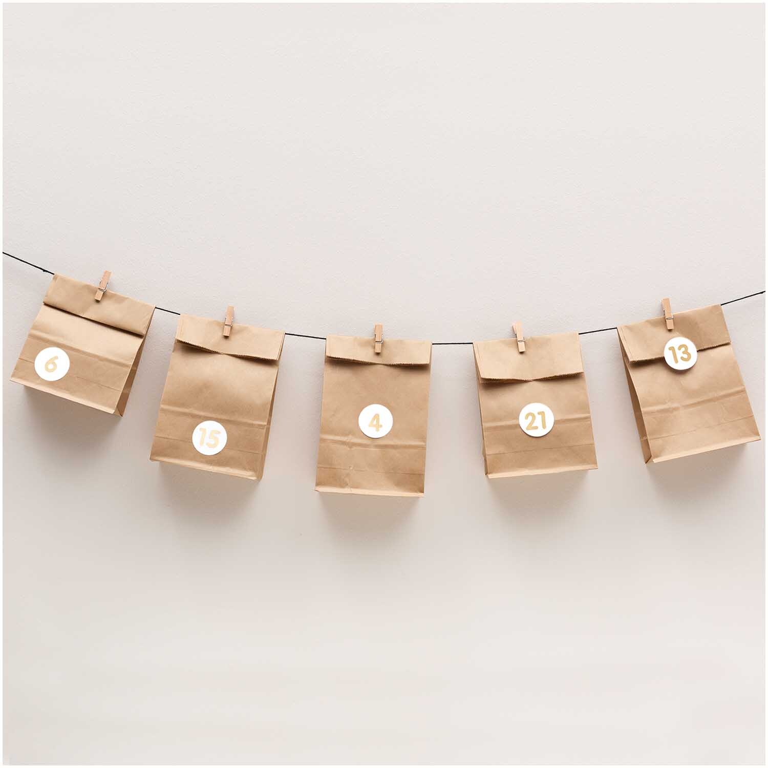 Paper Poetry Adventskalenderset mit 24 braunen Kraftpapiertüten, nummeriert, an Leine.