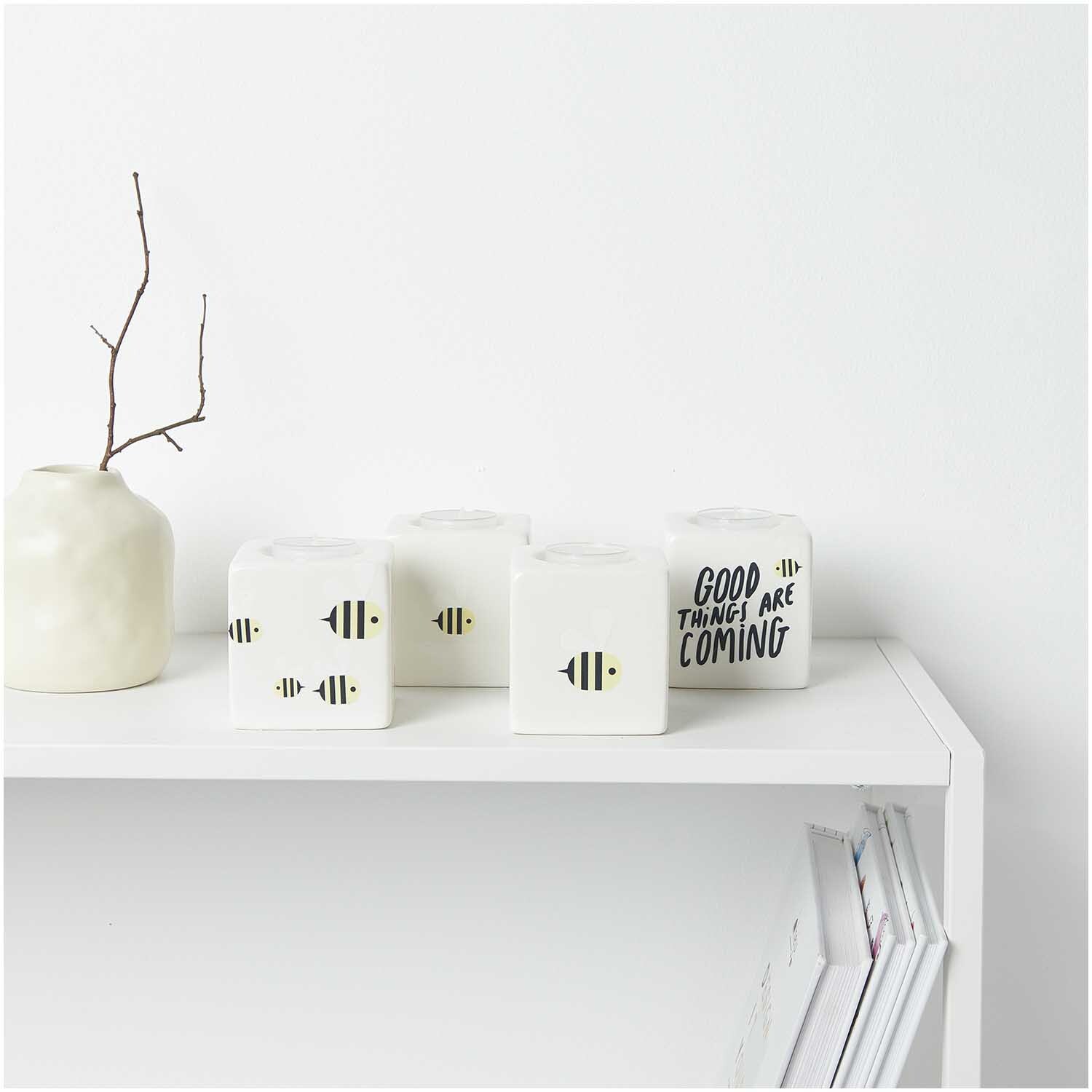 Transfermotiv Biene 15 Stück von Rico Design Transfermotiv Biene: Weiße Kerzen mit Bienenmuster und motivierendem Spruch auf einem Regal.