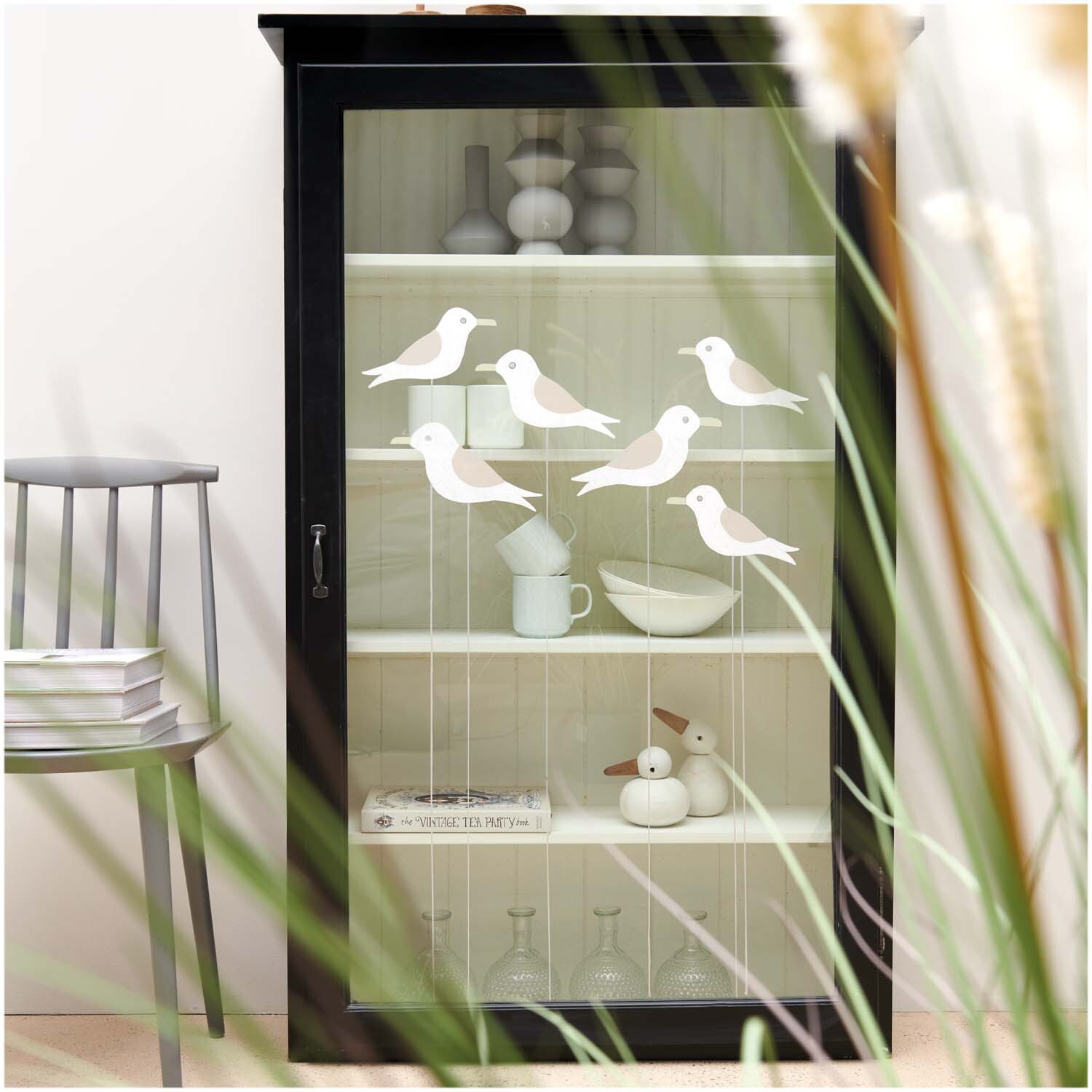 Vorlagenmappe Maritim: Ein schwarzer Schrank mit dekorativen Kreidestift-Vogelmotiven auf Glas.