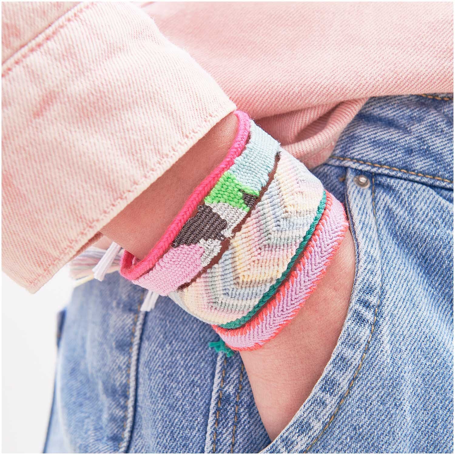 Set de fils à broder pastel 10 pièces 10-teilig from Rico Design Stickgarn Set Pastell: Armbänder aus buntem Garn von Rico Design, getragen an einem Handgelenk in einer Jeans.