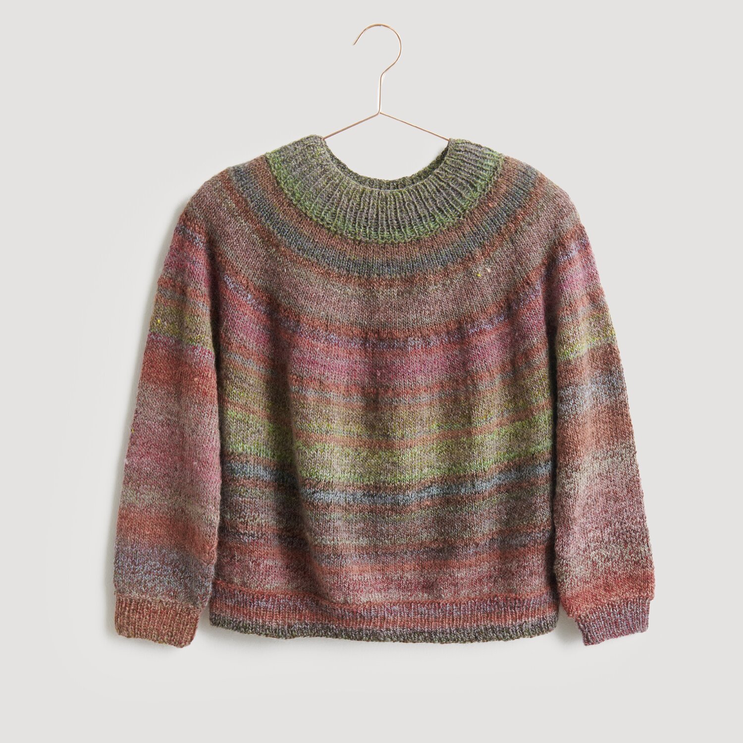 Creative Melange Alpaca Wonderball dk 100g 300m Farbe Forest von Rico Design Pullover in sanften, mehrfarbigen Tönen, präsentiert auf einem Kleiderbügel. Der Strickpullover von Modell Legeware besticht durch sein einzigartiges Design und die harmonische Farbgebung. Ideal für kühle Tage.