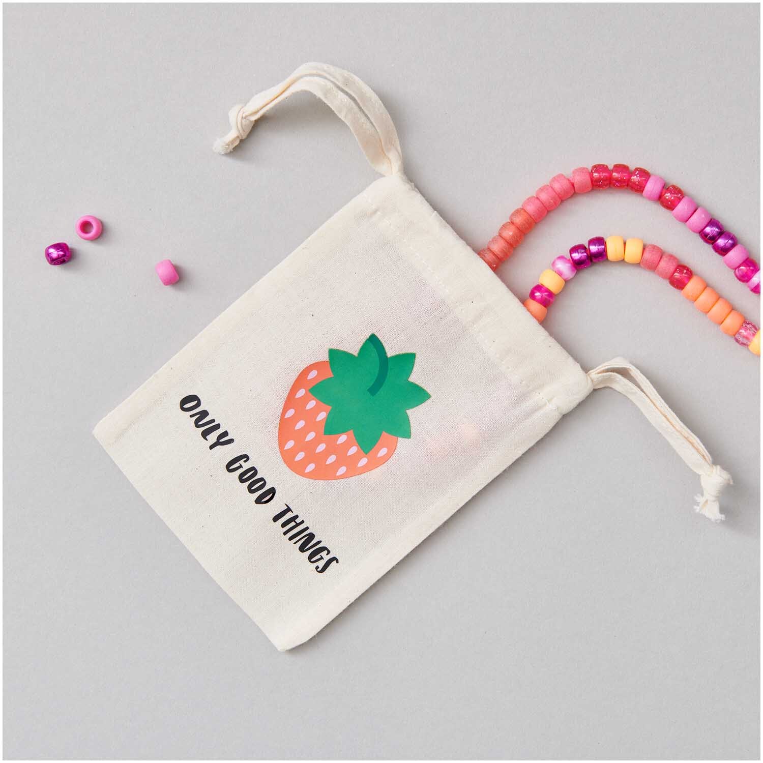 Bügelmotiv Erdbeeren 9 Stück: Stoffbeutel mit Erdbeerdesign und bunten Perlen auf grauem Hintergrund.
