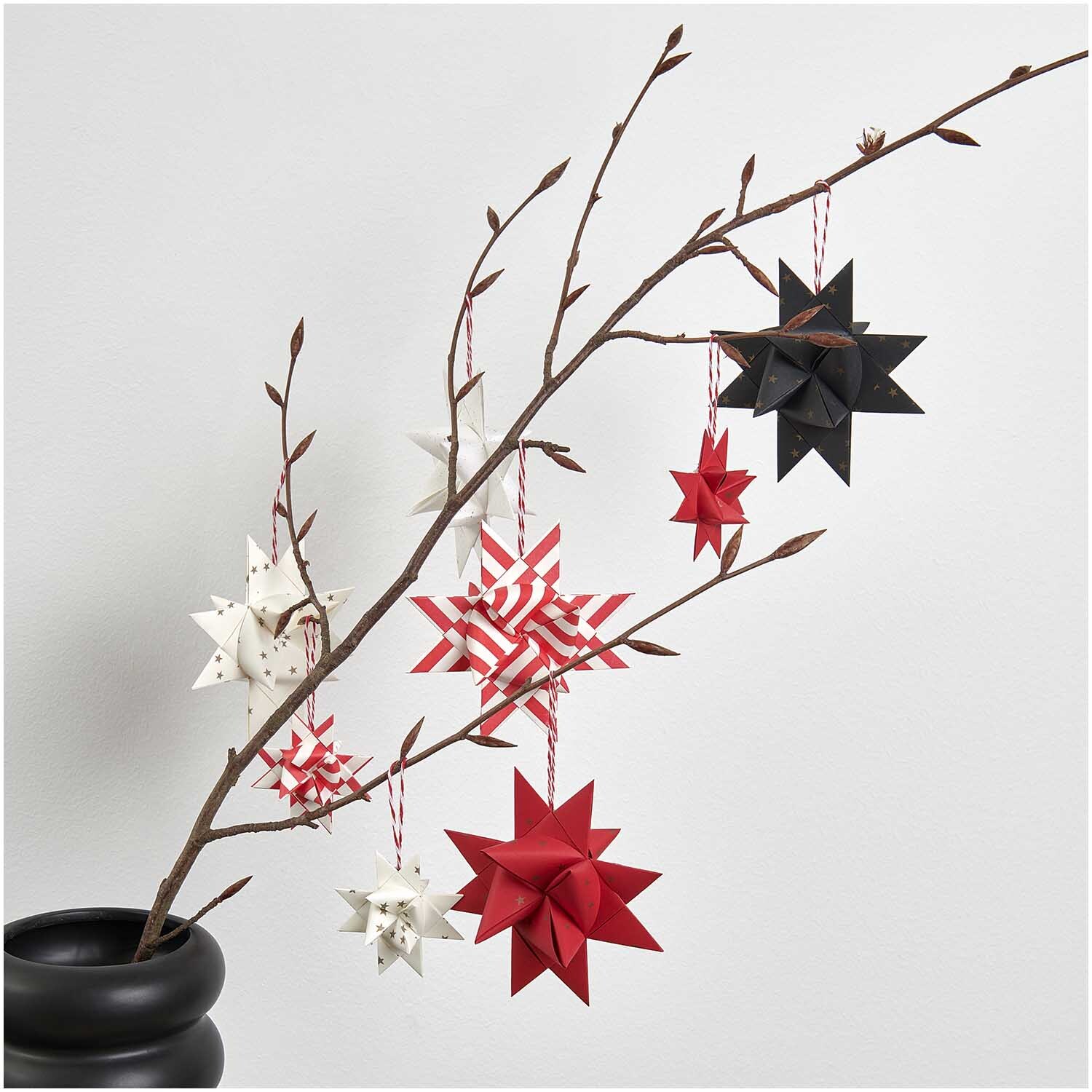 Paper Poetry Fröbelstreifen schwarz Sterne 60 Stück von Rico Design Paper Poetry Fröbelstreifen: Origami-Sterne in Schwarz, Rot und Weiß an einem Ast hängend.