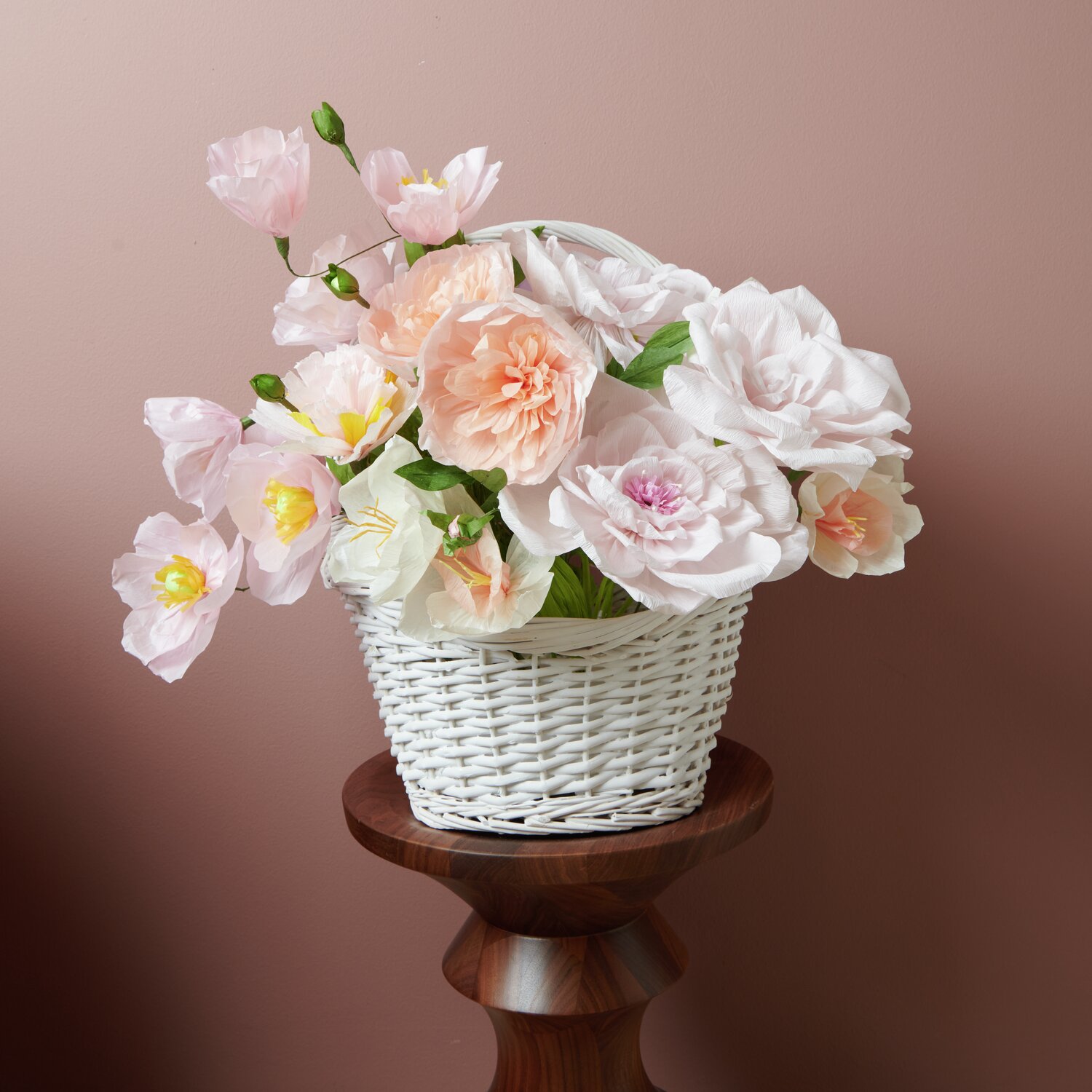 Papierblume Rose gefüllt Apricot: Ein Korb mit zarten Papierblumen in Apricot- und Rosatönen auf einem Holzsockel.