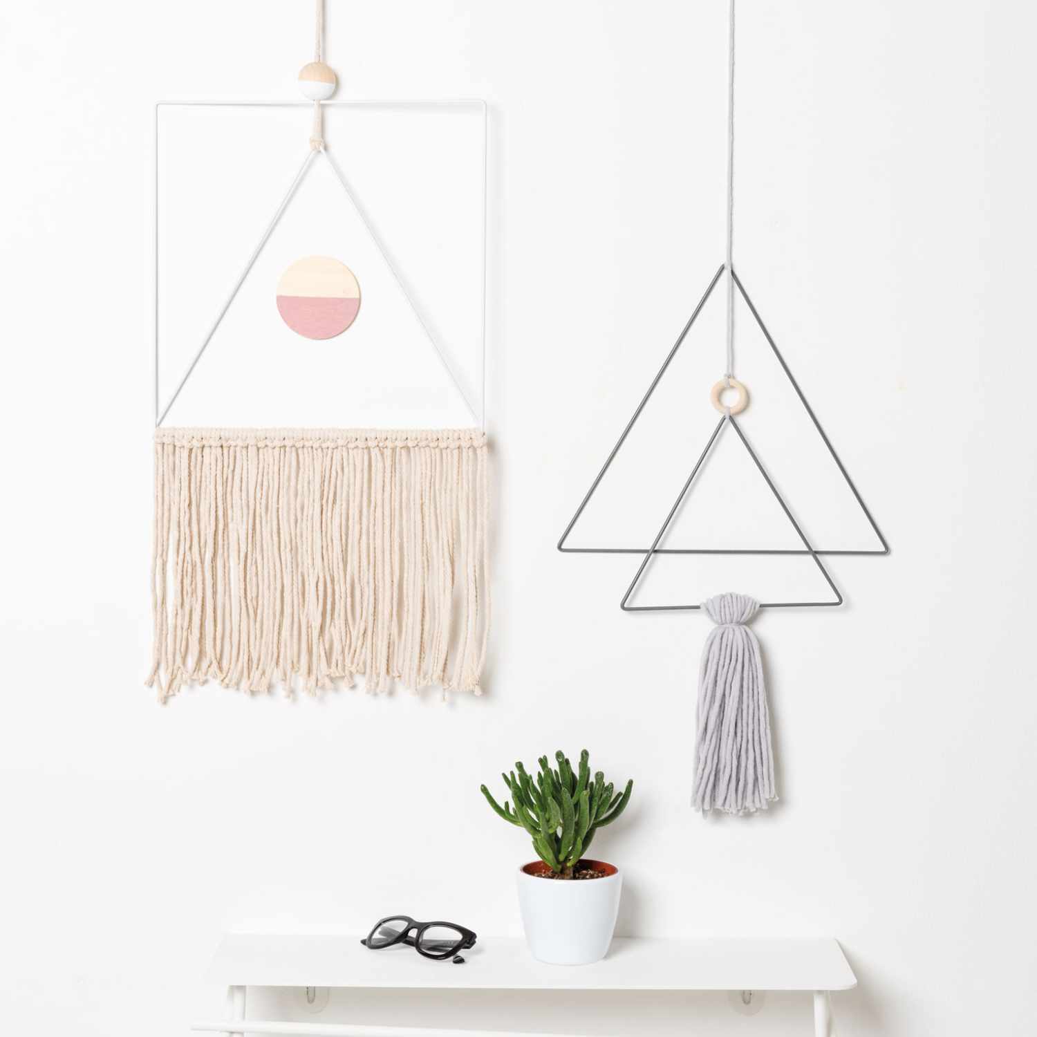 Creative Cotton Cord Makramee-Garn: Zwei geometrische Wandbehänge in Pastellfarben, dekorativ arrangiert über einem weißen Tisch mit Pflanze.