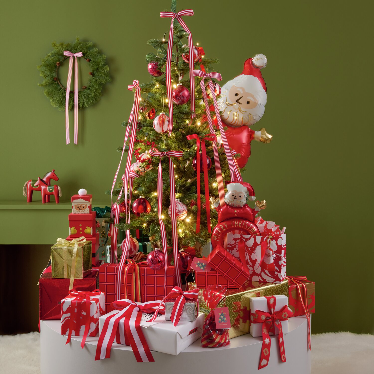 Paper Poetry bande tissée diagonale 50mm 3m Couleur Vert from Rico Design Papierschachtel-Set von Rico Design in Rot, bestehend aus 4 Stück, präsentiert vor einem festlich geschmückten Weihnachtsbaum mit Geschenken und Dekorationen. Perfekt für kreative Geschenkverpackungen.
