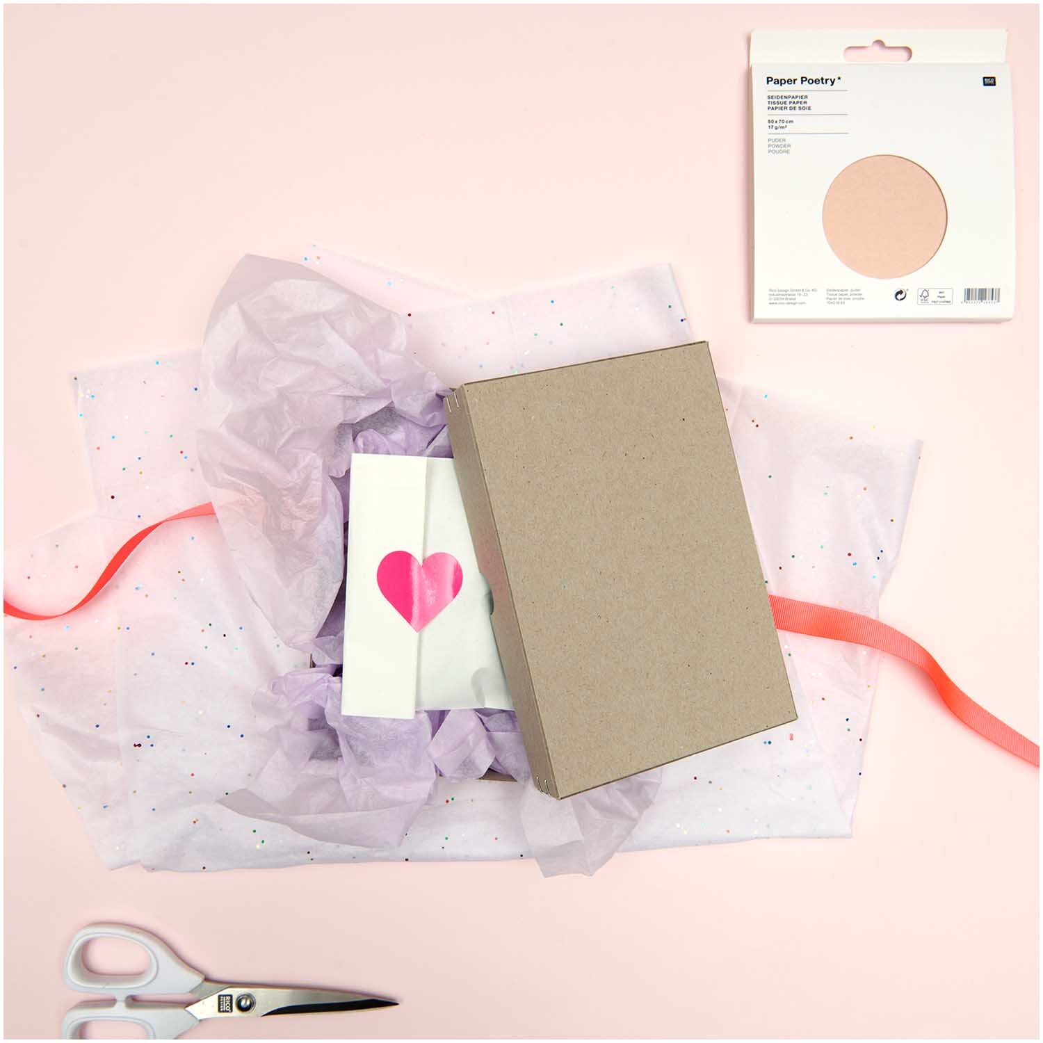 Paper Poetry Seidenpapier 50x70cm 17g/m² 5 Bogen Farbe Helllila von Rico Design Paper Poetry Seidenpapier in Helllila, dekorativ arrangiert mit Geschenkbox, Karte und Schere auf rosa Hintergrund. Ideal für kreative Verpackungen.