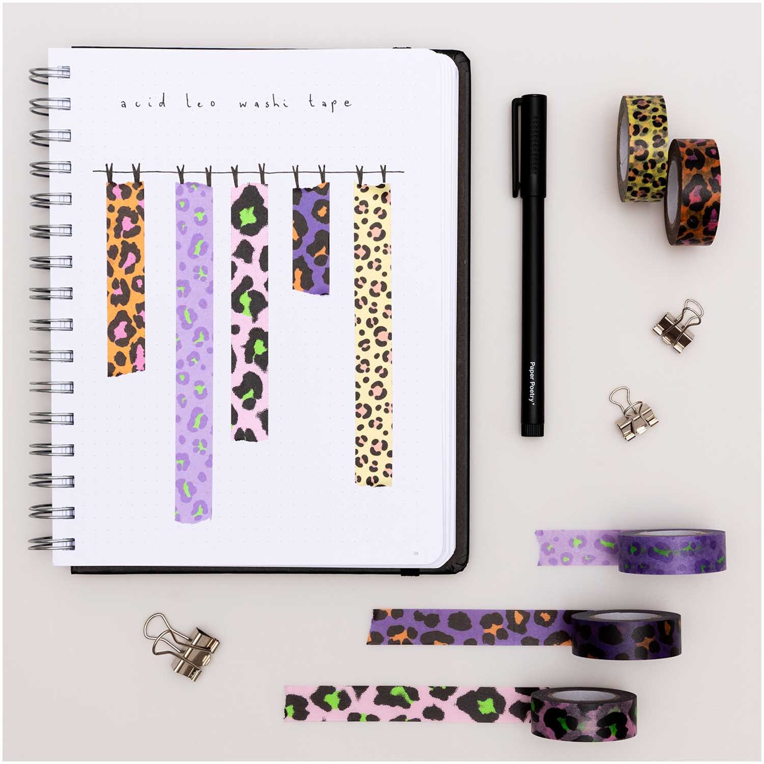 Paper Poetry Tape Set Acid Leo 5-teilig von Rico Design Paper Poetry Tape Set Acid Leo: Fünf bunte Washi-Tapes mit Leopardenmuster von Rico Design, arrangiert neben einem Notizbuch und Stift.