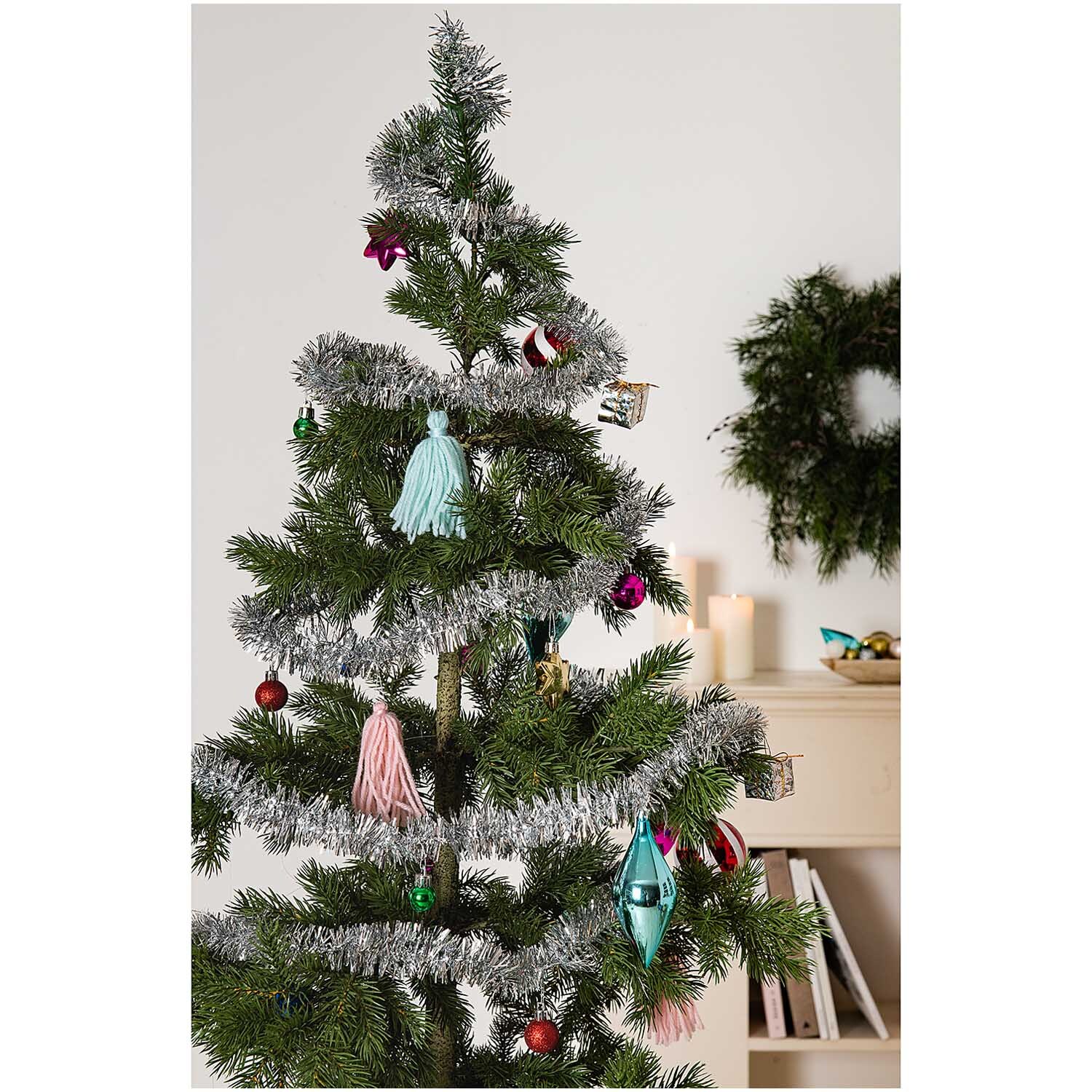 Girlande Lametta mit Dekor 2,5m von Rico Design Girlande Lametta mit Dekor 2,5m schmückt einen Weihnachtsbaum mit buntem Schmuck und Lametta. Im Hintergrund sind Kerzen und ein Kranz zu sehen.