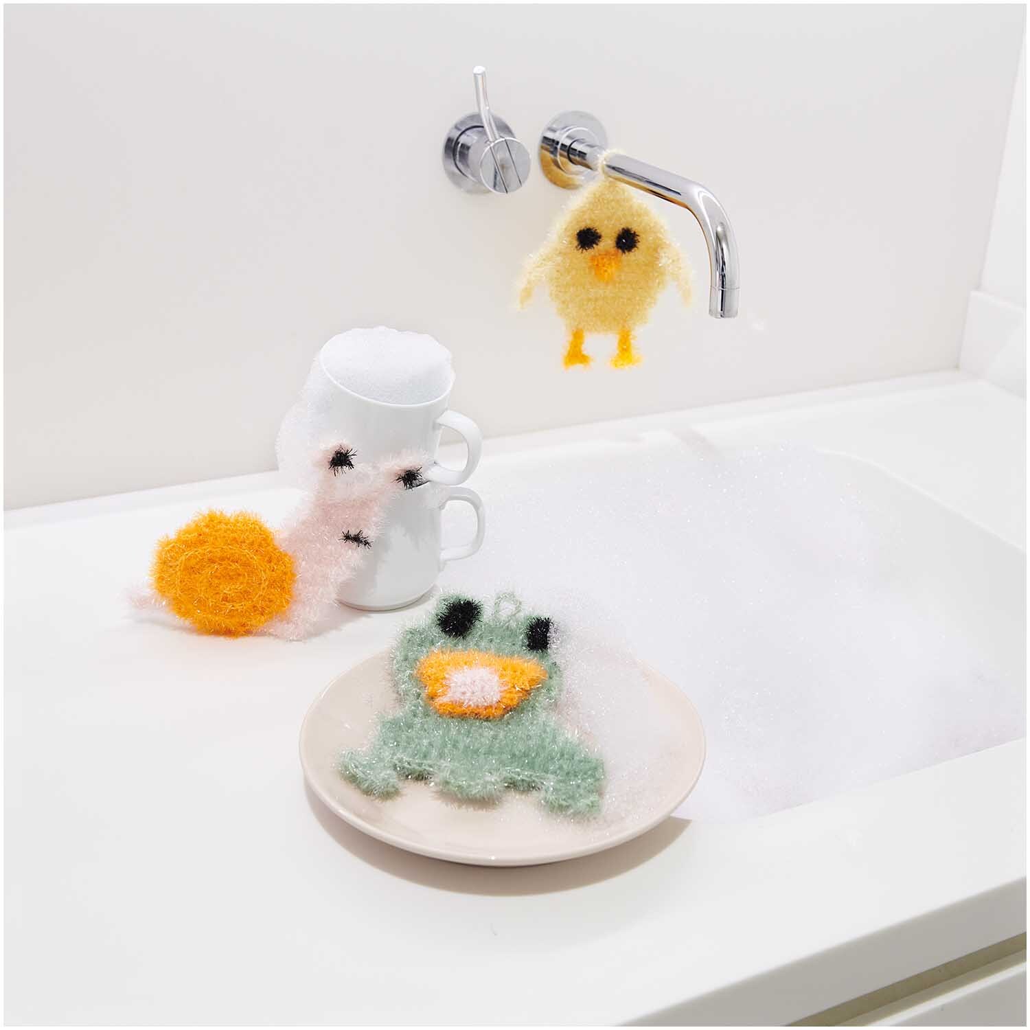 Häkelset Creative Bubble Kleine Tierchen von Rico Design Häkelset Creative Bubble Kleine Tierchen von Rico Design: Bunte gehäkelte Schwämme in Tierform neben einem Waschbecken.