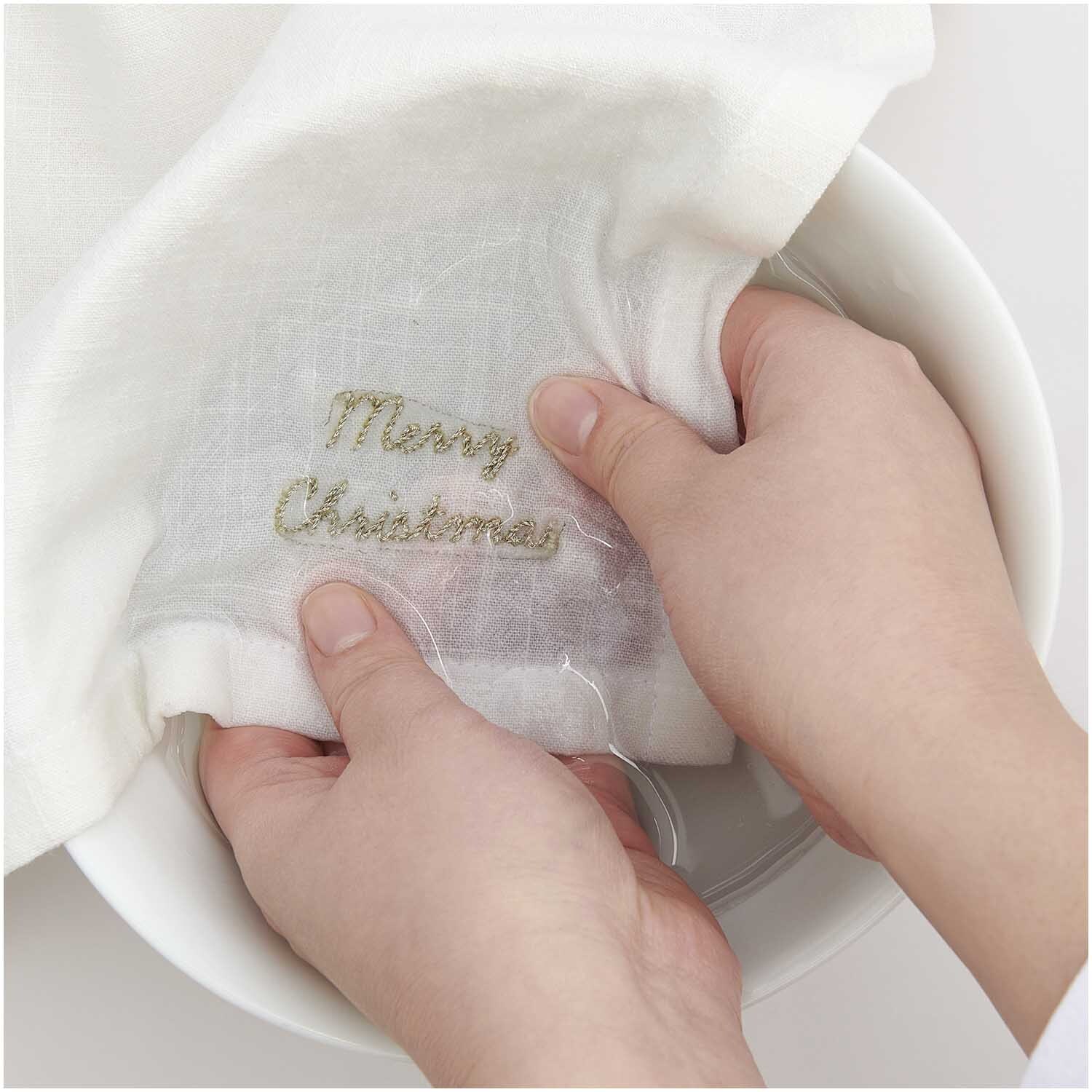 Stick and Stitch Stickpackung Merry Christmas vorgezeichnet von Rico Design Stick and Stitch Stickpackung Merry Christmas vorgezeichnet: Hände halten ein weißes Tuch mit gesticktem "Merry Christmas" von Rico Design.