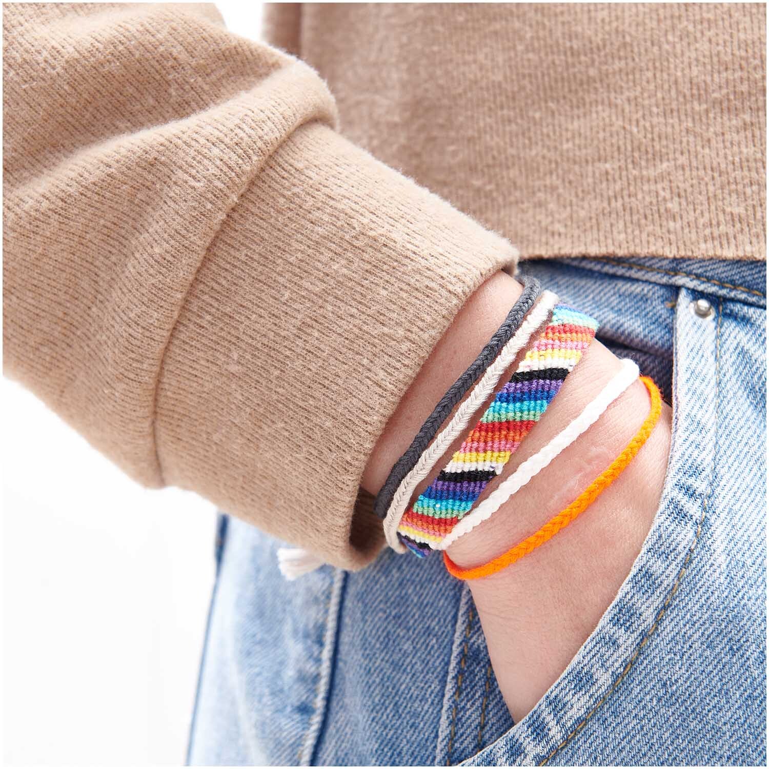 Set de fils à broder Multicolour Fashion 24 pièces 24-teilig from Rico Design Stickgarn Set Multicolour Fashion: Handgelenk mit bunten Armbändern aus mehrfarbigem Garn von Rico Design, lässig in Hosentasche gesteckt.
