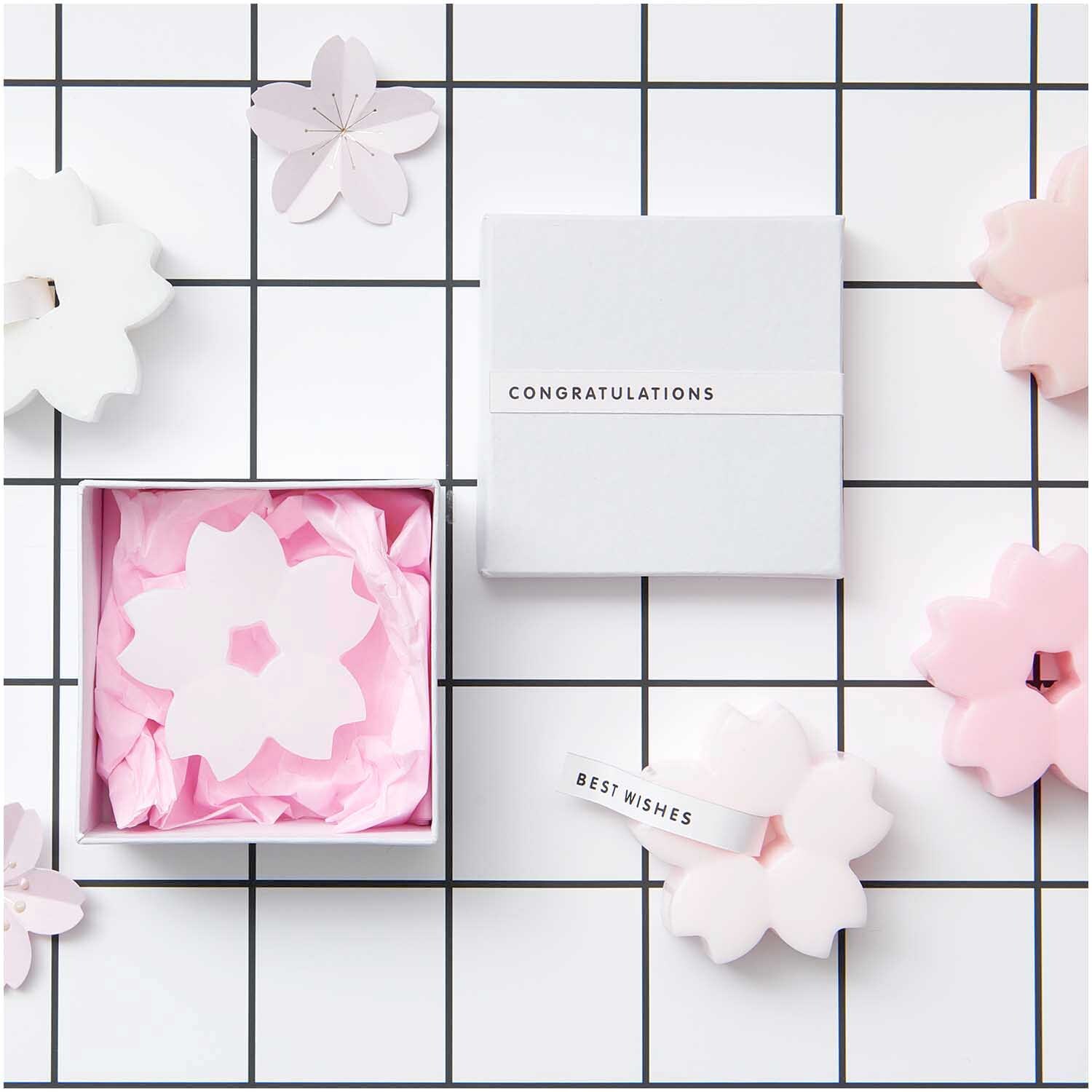 Quadratbox weiß Größe 9x9x4,5 cm von Rico Design Quadratbox weiß mit Blumenmotiv auf kariertem Hintergrund, dekoriert mit rosa Blüten und Glückwunschband.