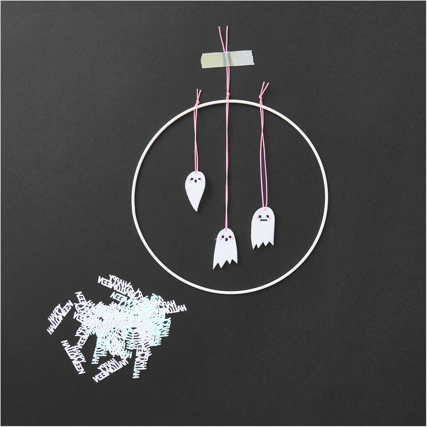 Filzstreu Gespenst Mix weiß 12 Stück von Rico Design Filzstreu Gespenst Mix weiß 12 Stück: Drei weiße Filzgespenster hängen an rosa Fäden in einem Ring, daneben liegt Filzstreu.