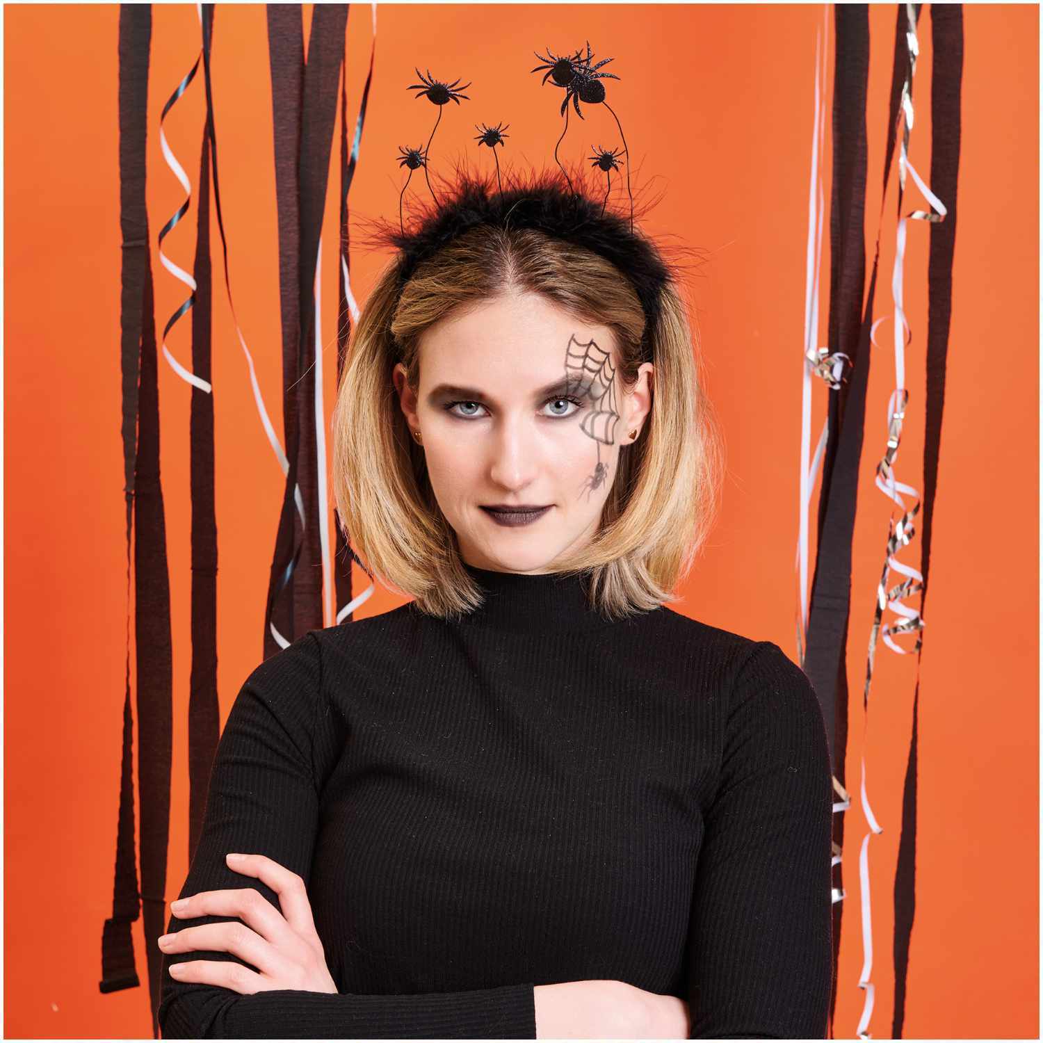 Haarreif Spinnen schwarz von Rico Design Haarreif Spinnen schwarz: Frau mit schwarzem Spinnen-Haarreif vor orangefarbenem Hintergrund.