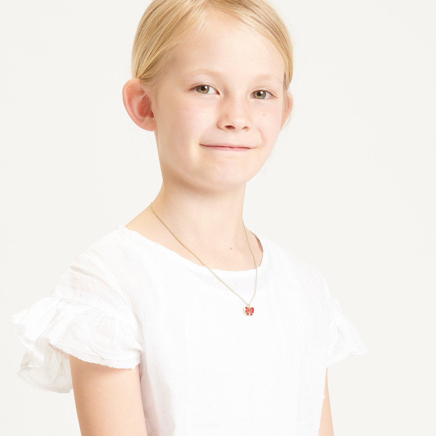 Kette mit Anhänger Schleife 40cm Farbe Rot von Rico Design Kette mit Anhänger Schleife, 40cm, in elegantem Rot, getragen von einem Kind in weißem Kleid.