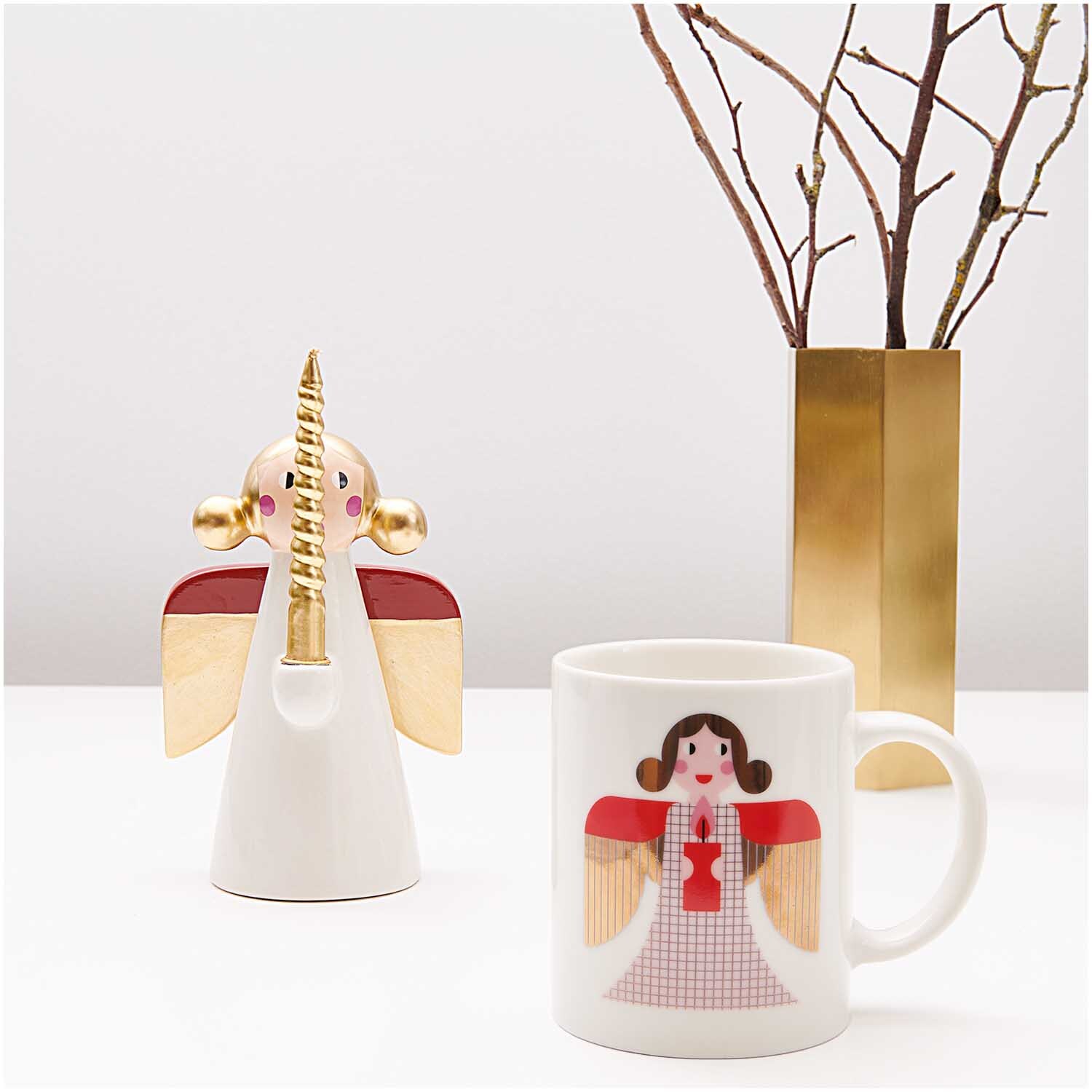 Porzellan Tasse Engel 8x9,5cm von Rico Design Porzellan Tasse Engel 8x9,5cm mit Engelmotiv in Rot und Gold, neben einer goldenen Vase.