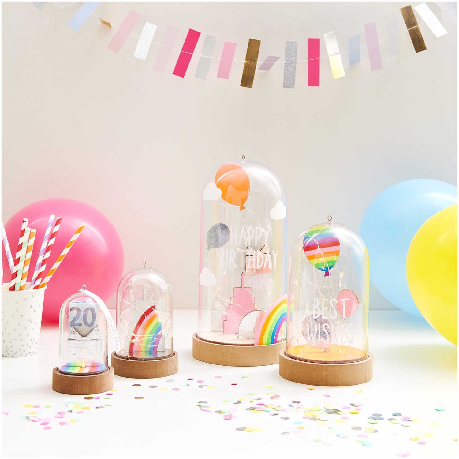 Dekohaube mit Sockel 5,5x11cm Gr. S von Rico Design Dekohaube mit Sockel 5,5x11cm Gr. S von Rico Design zeigt bunte Ballons und Regenbogen auf einem Tisch mit Konfetti und Luftballons.