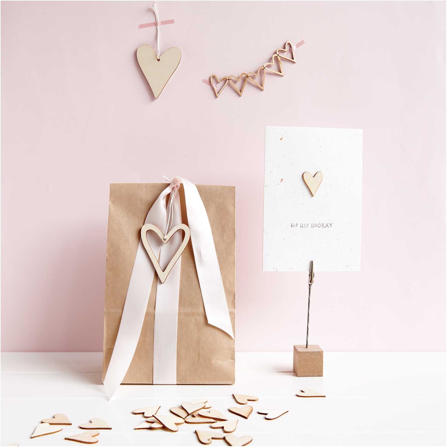 Holzhänger Herz offen natur von Rico Design Holzhänger Herz offen natur von Rico Design, dekoriert auf einer Geschenkverpackung mit Herzmotiven.
