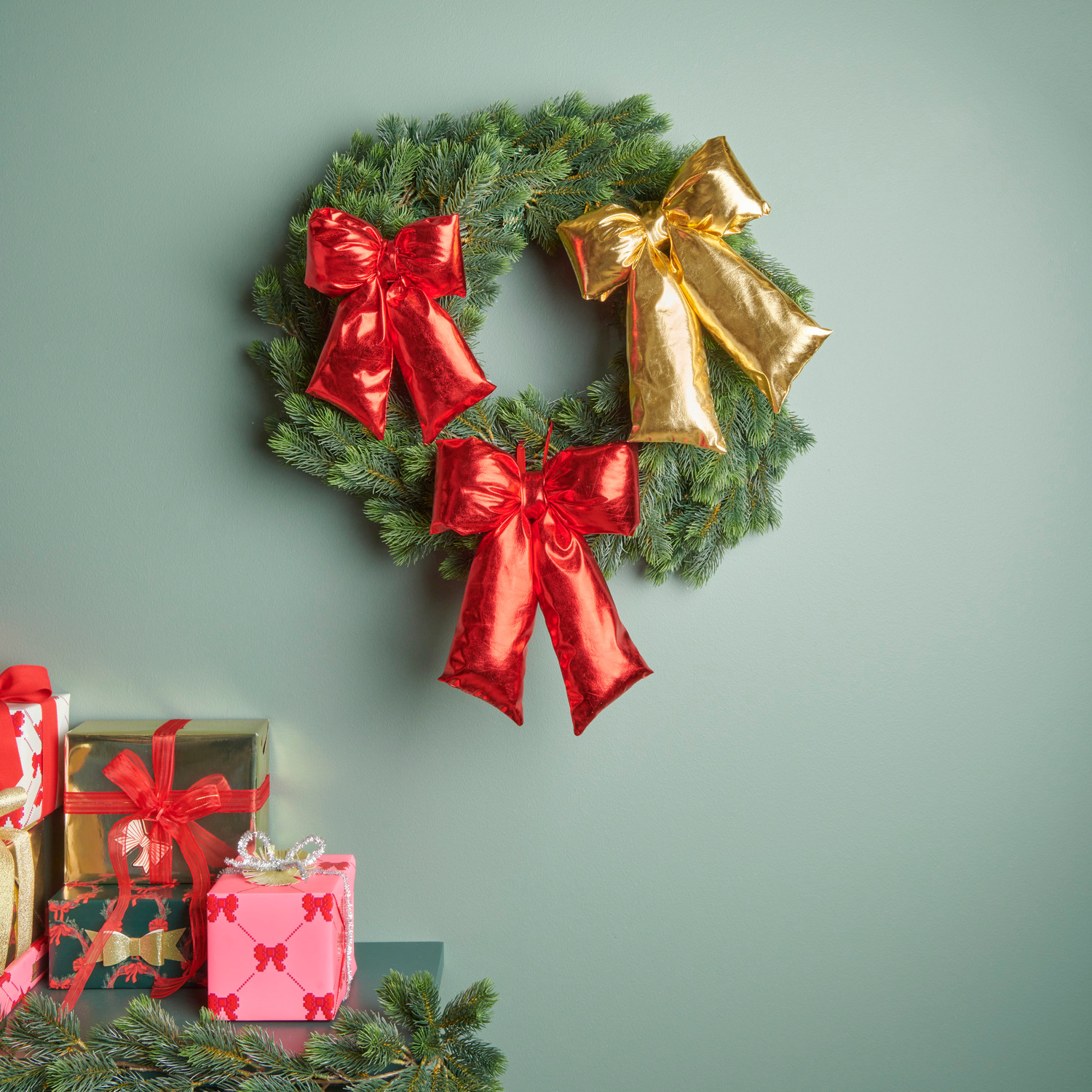 Weihnachtsschleife Rot Größe 24x19x5cm von Rico Design Weihnachtsschleife Rot: Festlicher Kranz mit roten und goldenen Schleifen, dekoriert auf grünem Hintergrund.