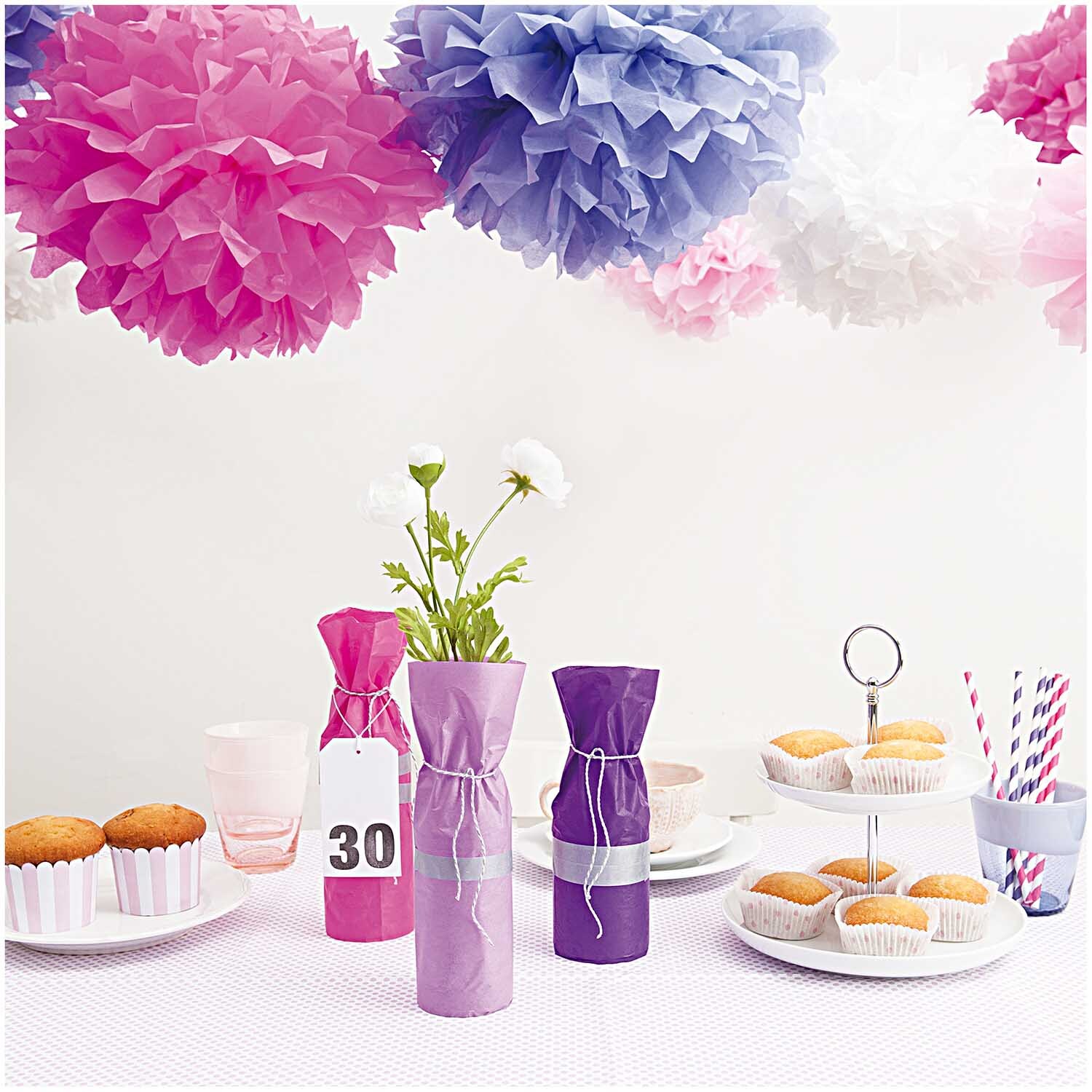 Seidenpapier Pompons 17g/m² 3 Stück in verschiedenen Farben dekorieren einen Tisch mit Gebäck und Getränken.