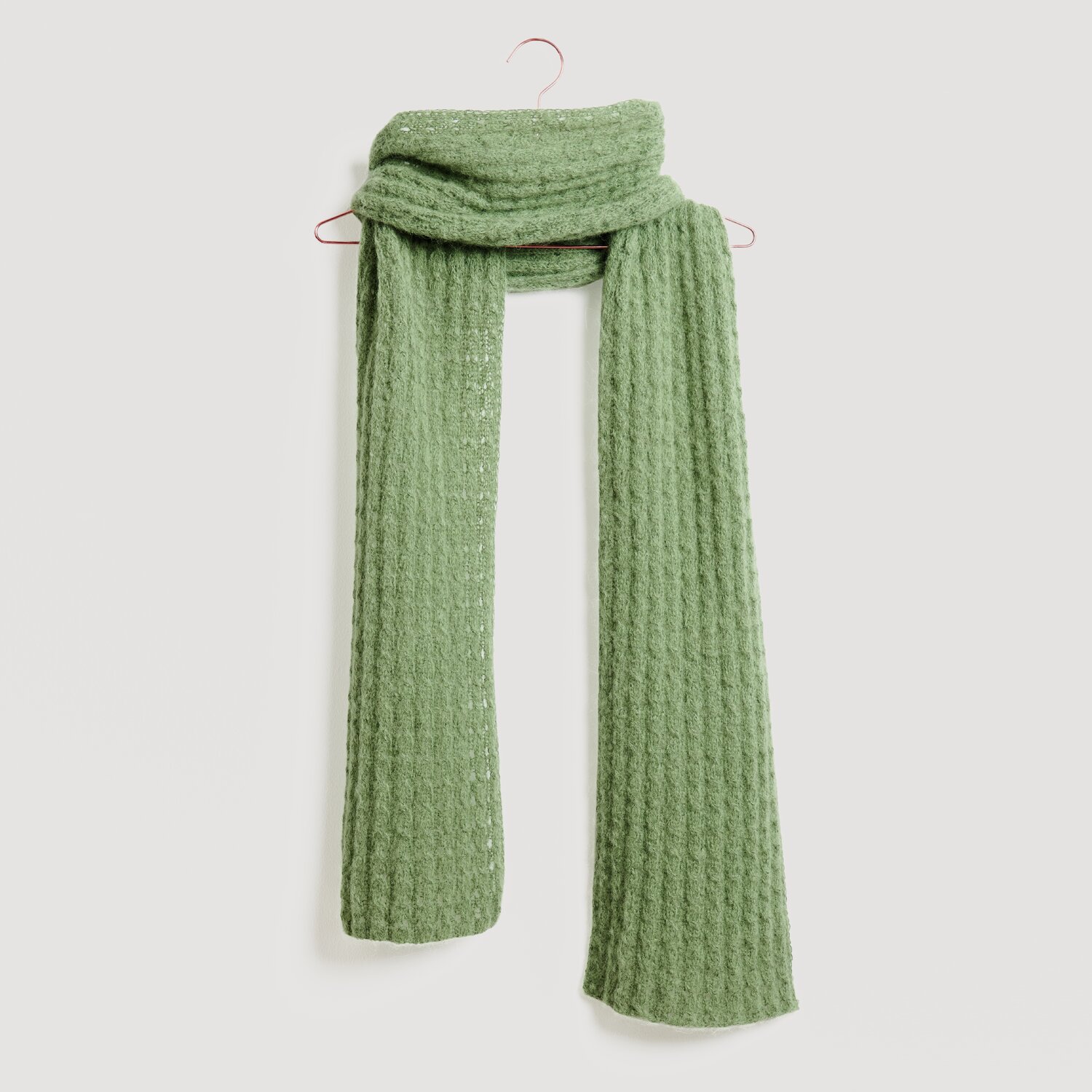 Luxury Alpaca Cotton Fusion 50g 190m Farbe Aloe von Rico Design Grüner Schal von Modell Legeware, elegant drapiert auf einem Haken. Der Schal hat eine strukturierte Oberfläche und bietet stilvolle Wärme für kalte Tage. Ideal für modische Akzente.