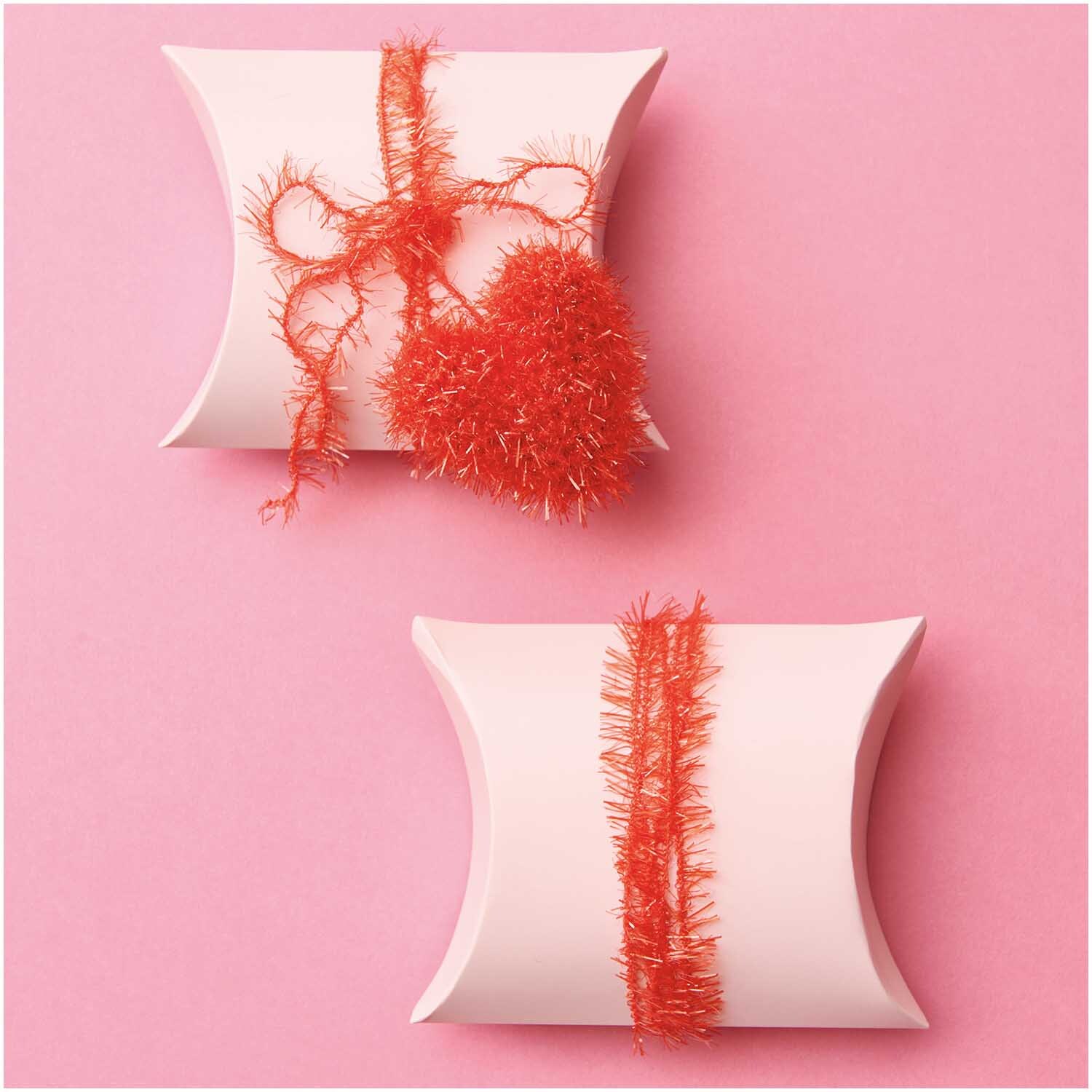 Creative Bubble Set Good Luck! 10x50g von Rico Design Creative Bubble Set Good Luck! Zwei weiße Geschenkboxen mit rotem Garn auf rosa Hintergrund. Ideal für kreative Projekte von Rico Design.