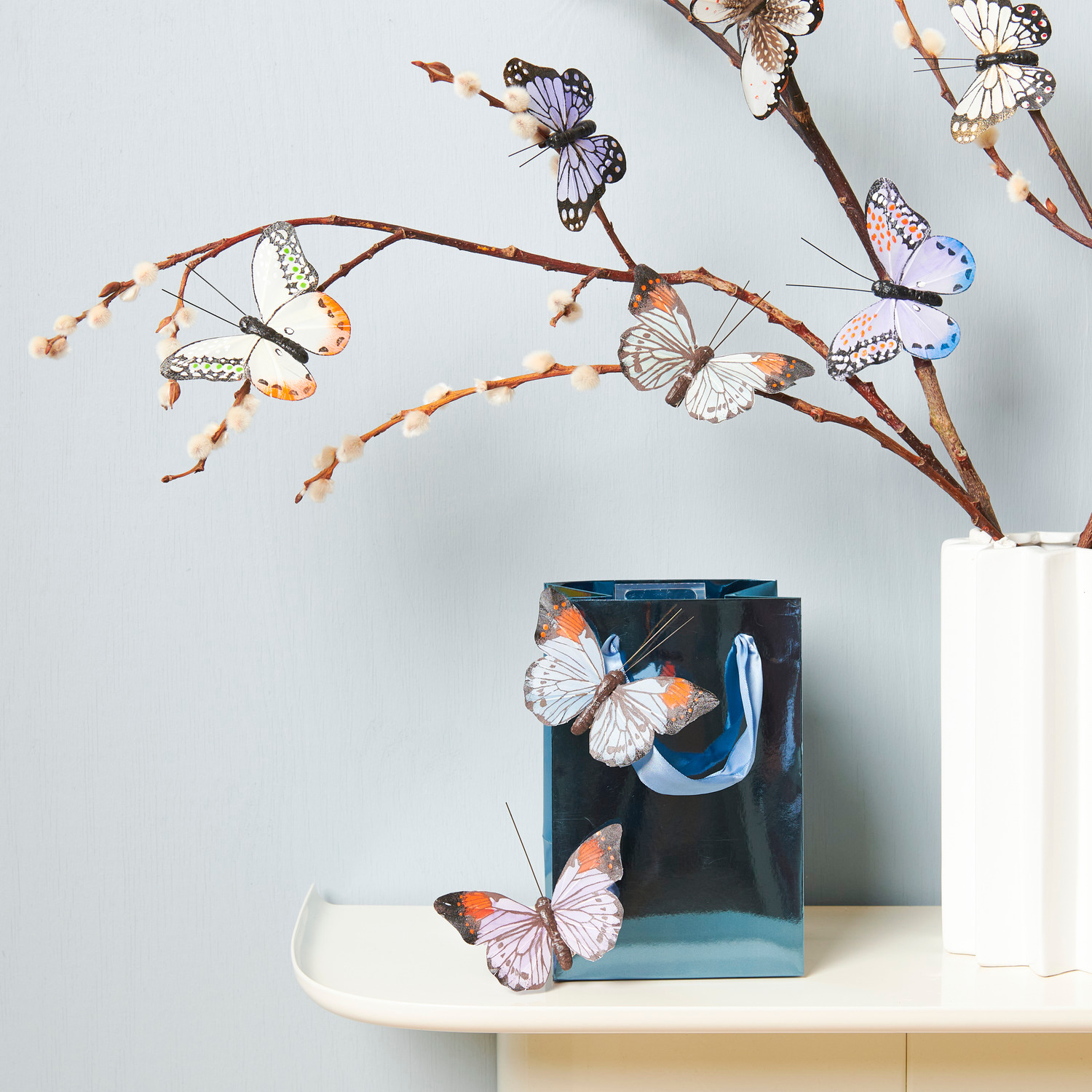 Keramik Vase Sonne weiß von Rico Design Schmetterling mit Clip Blau/Grün: Dekorative Schmetterlinge an Zweigen in einer weißen Keramikvase von Rico Design.