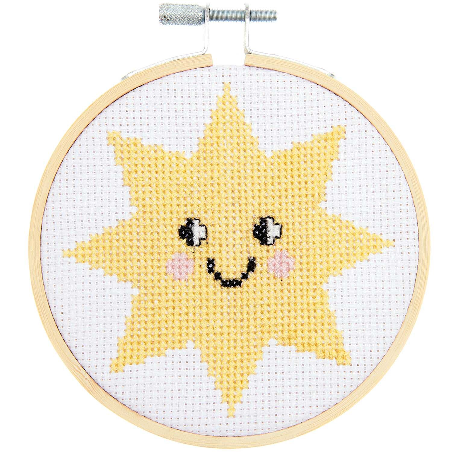 Stickpackung Happy Sun: Ein gelbes, lächelndes Sonnenmotiv in einem Stickrahmen von Rico Design.
