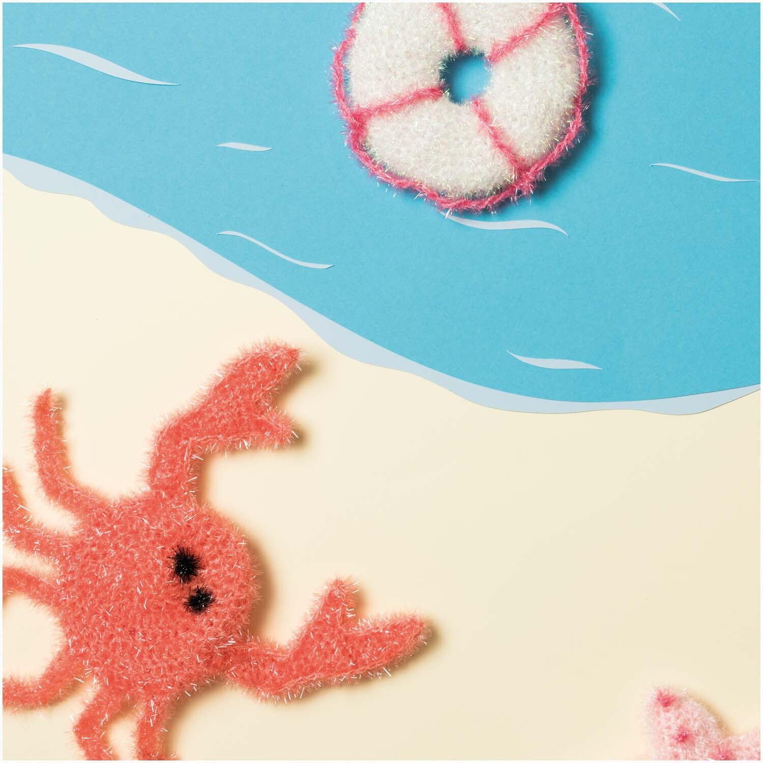 Creative Bubble - Beyond the Sea: Ein roter Krabben-Schwamm und ein Rettungsring auf sandigem Hintergrund. Ideal für kreative Projekte.