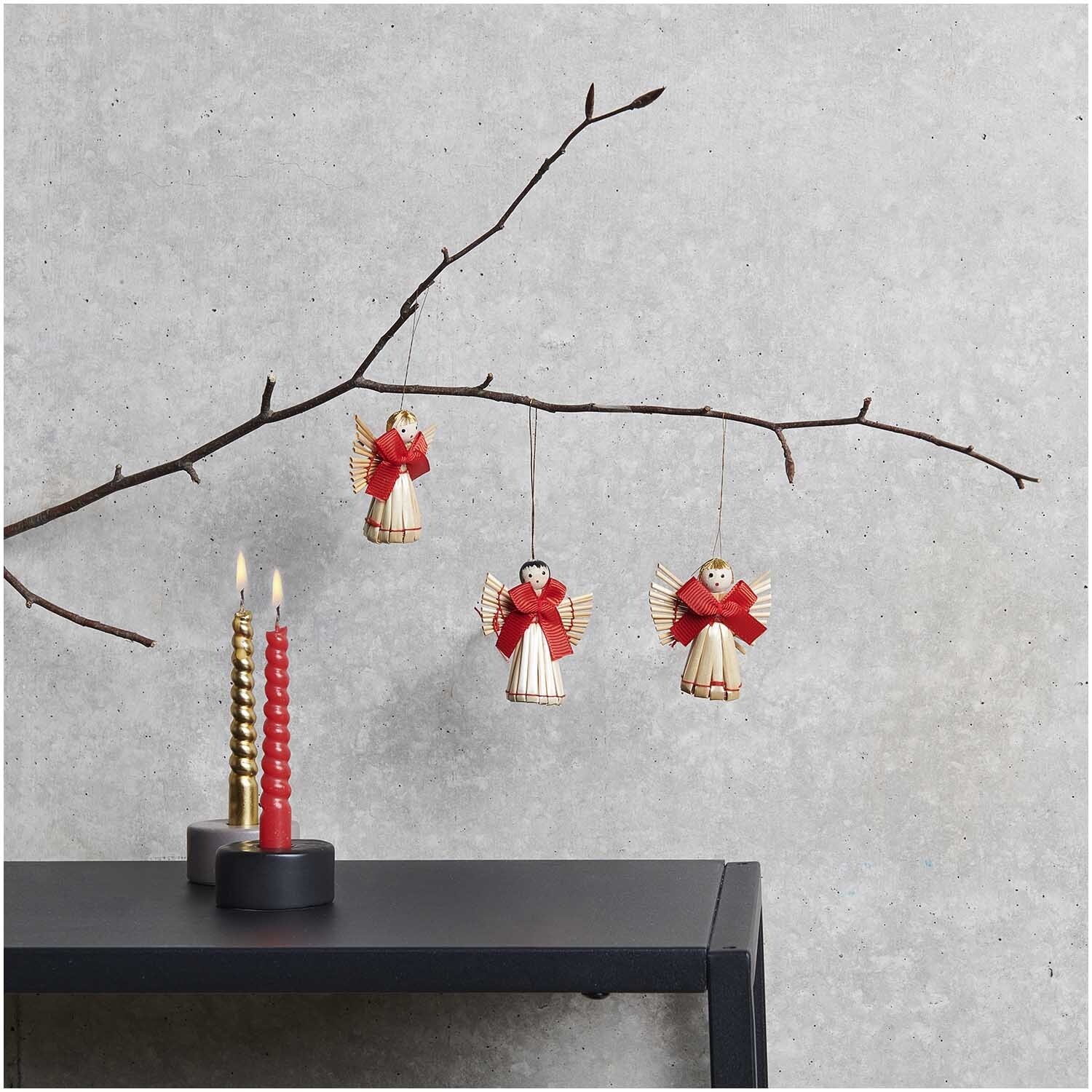 Strohengel-Set 5,5x5cm: Drei Strohfiguren mit roten Schleifen hängen an einem Ast, dekorativ arrangiert.