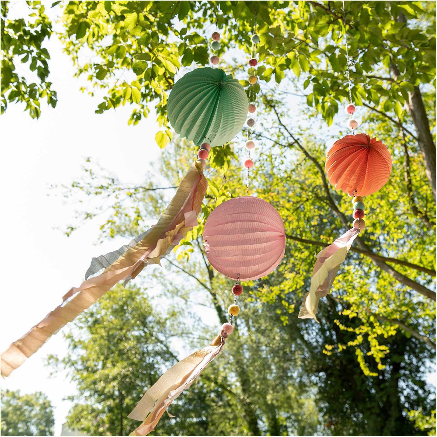 Garn Pompons 24 Stück Farbe Pastell Mix von Rico Design Garn Pompons 24 Stück: Bunte Pompons von Rico Design hängen dekorativ an einem Baum im Freien.
