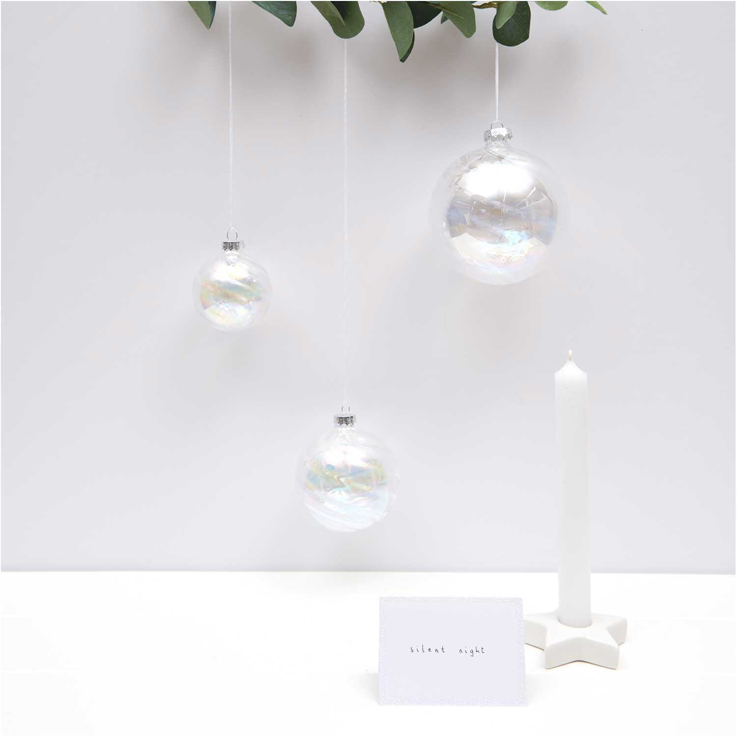 Paper Poetry Tischkarten weiß-glitter 9x12,7cm 6 Stück von Rico Design Paper Poetry Tischkarten in elegantem Weiß-Glitter, dekoriert neben schwebenden Glaskugeln und einer Kerze. Ideal für festliche Anlässe.