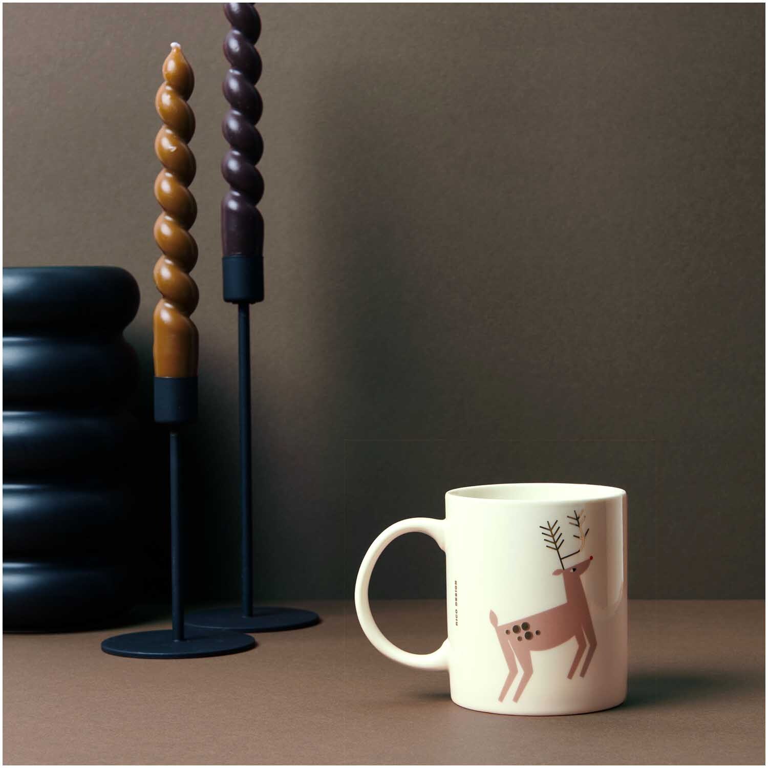 Porzellan Tasse Rentier 8x9,5cm von Rico Design Porzellan Tasse Rentier 8x9,5cm von Rico Design neben dekorativen, gedrehten Kerzen.