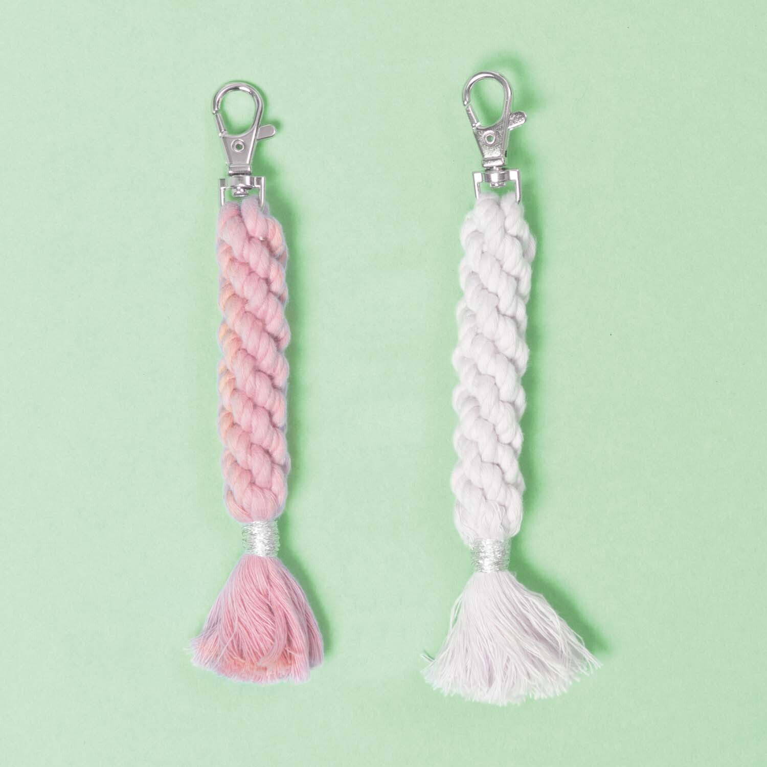 Creative Cotton Cord Makramee-Garn: Zwei geflochtene Schlüsselanhänger in Rosa und Weiß auf grünem Hintergrund.