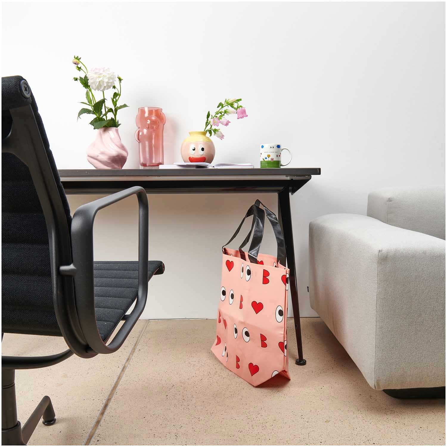 Rico Design x Redfries Shopper Liebe rosa 54x43x20cm von Rico Design Rico Design x Redfries Shopper Liebe in Rosa neben einem modernen Schreibtisch mit Blumenvasen.
