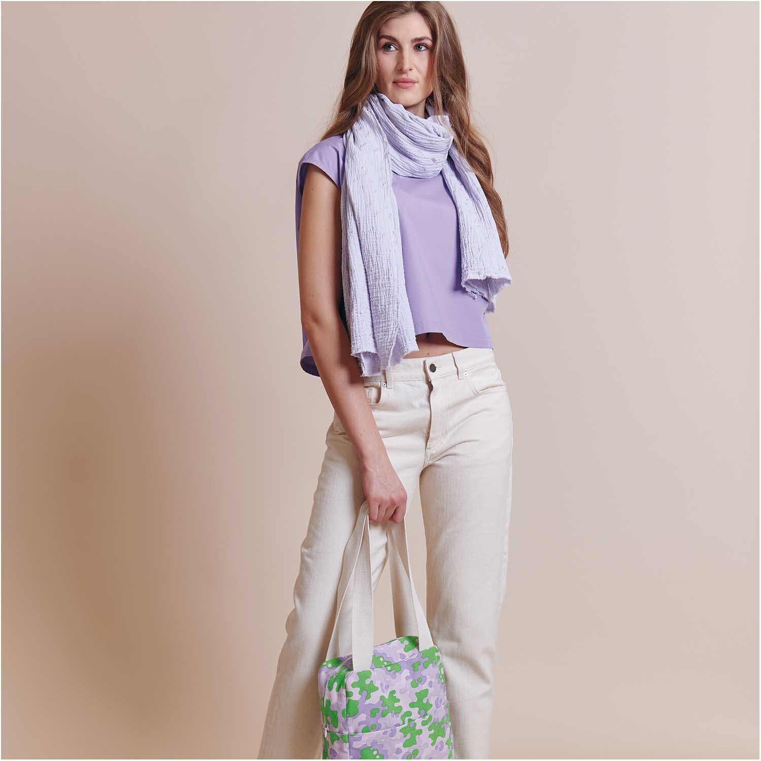 Meterware Krinkelmusselin hellgrau Hot Foil von Rico Design Meterware Krinkelmusselin hellgrau Hot Foil: Frau in lila Oberteil mit hellgrauem Schal und Tasche mit Blumenmuster.