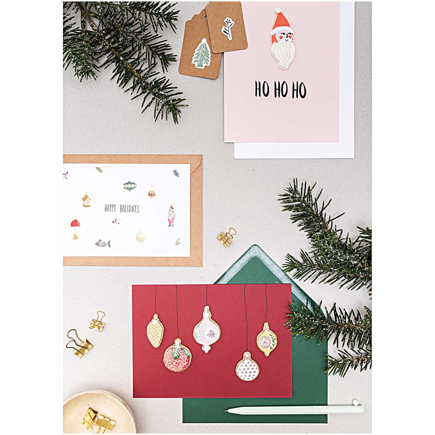 Paper Poetry Gelsticker Nostalgic Christmas classic von Rico Design Paper Poetry Gelsticker Nostalgic Christmas classic von Rico Design zeigt festliche Karten mit Weihnachtsmotiven und Tannenzweigen auf einem Tisch.