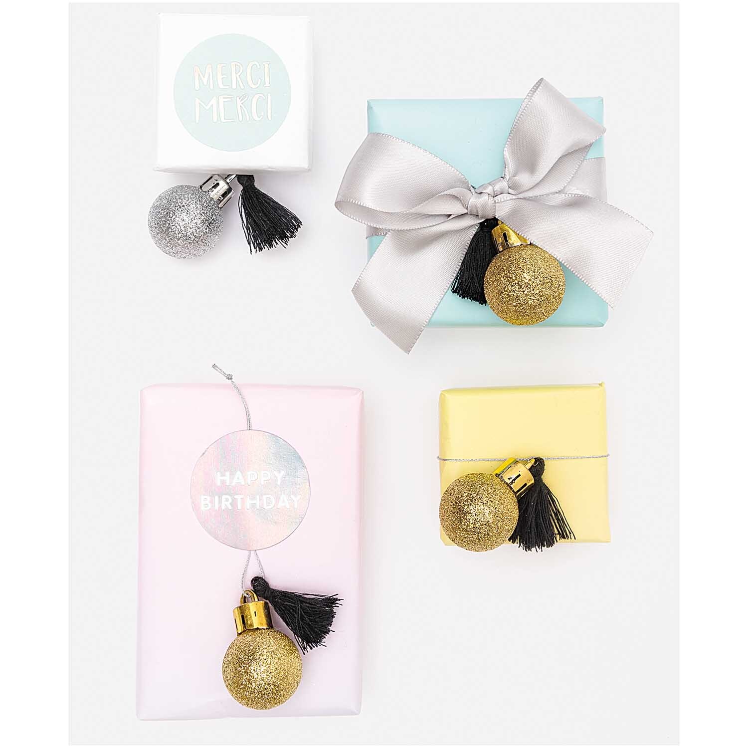 Mini-Kugel-Anhänger gold-silber 6 Stück von Rico Design Mini-Kugel-Anhänger gold-silber 6 Stück, dekorativ auf Geschenkboxen in Pastellfarben arrangiert.