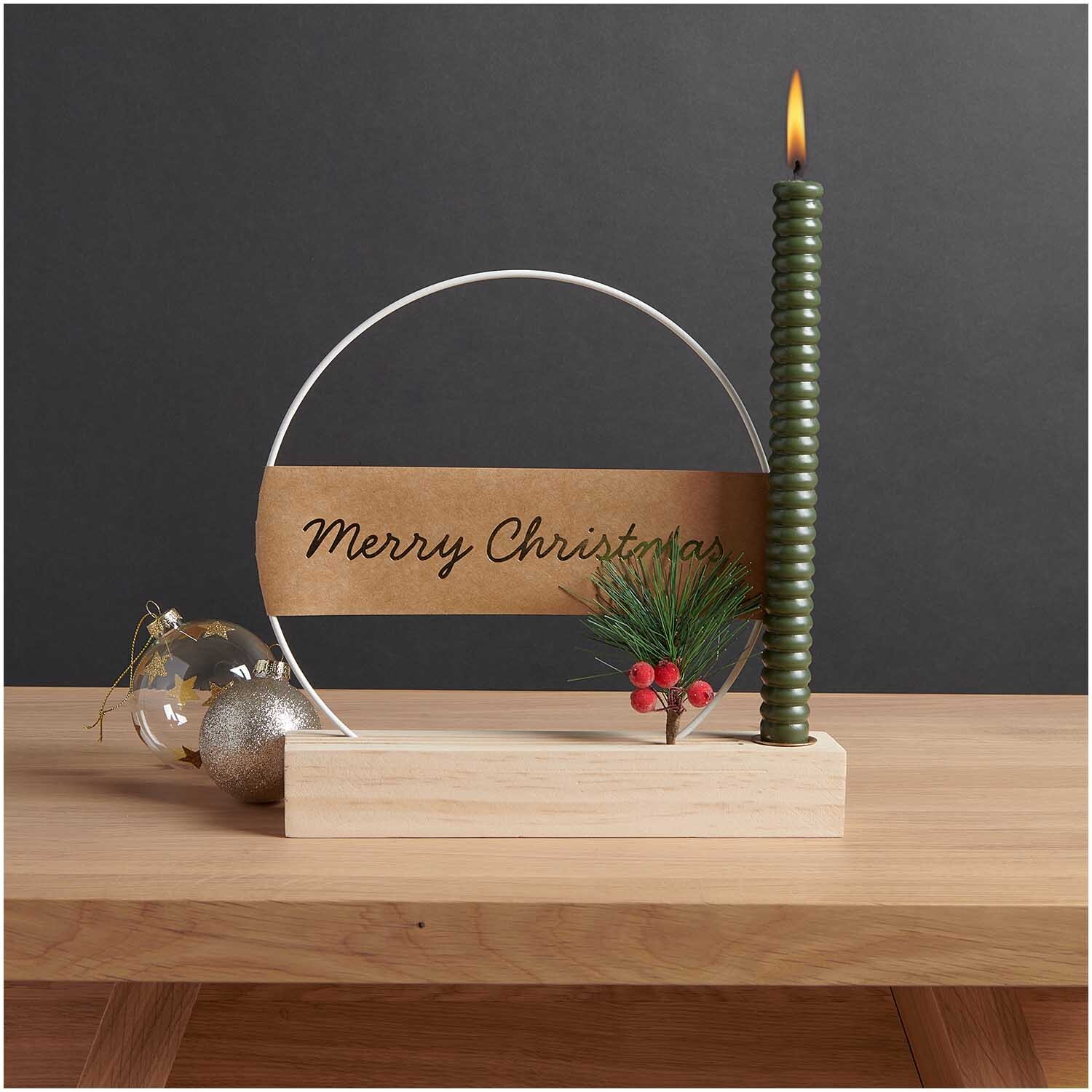 Holzständer für Metallringe & Karten mit Kerzenhalter, dekoriert mit grüner Kerze und Weihnachtskugel auf Holztisch.
